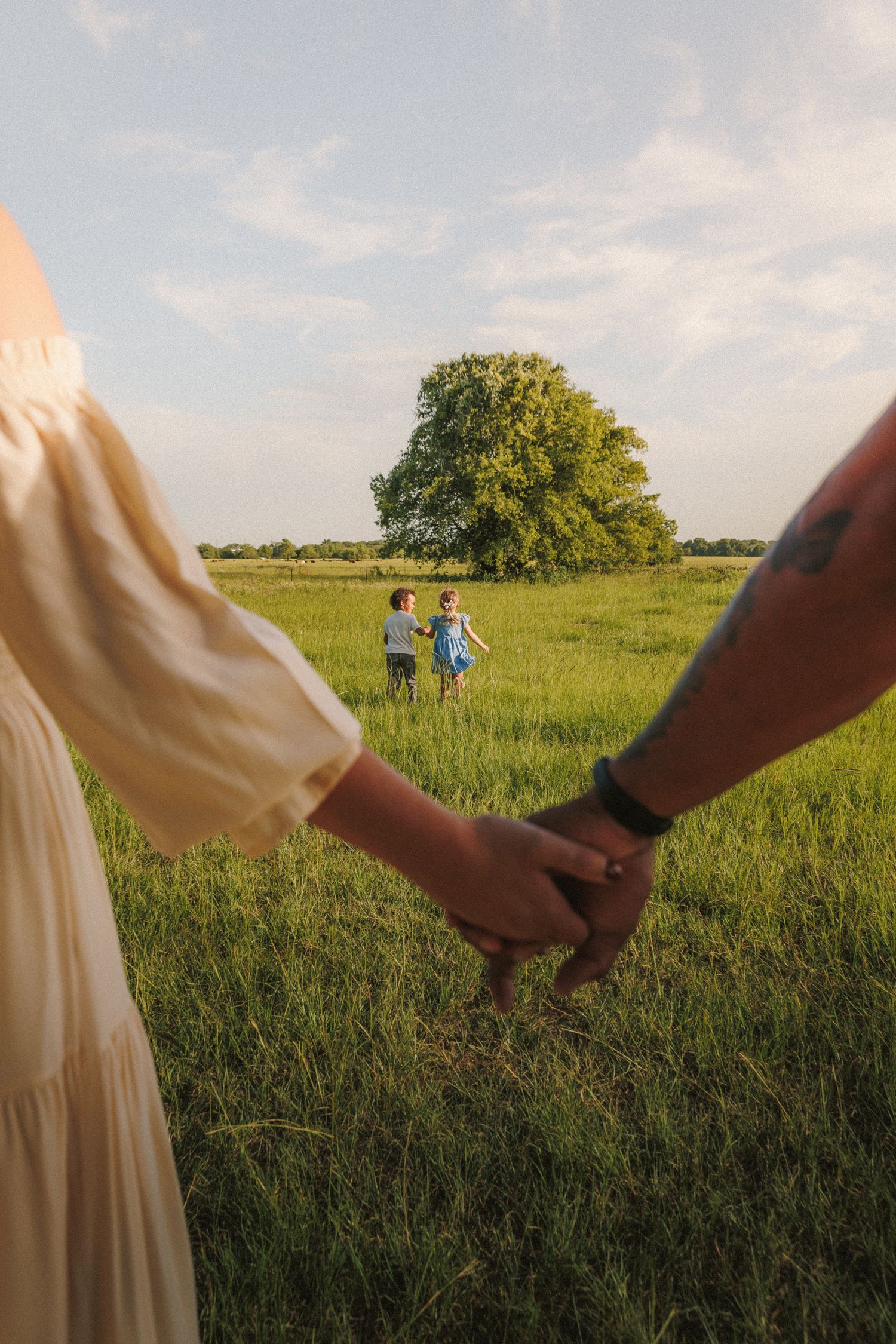 Two people holding hands walk through a sunlit meadow while shot in a sequence of progression across the field.