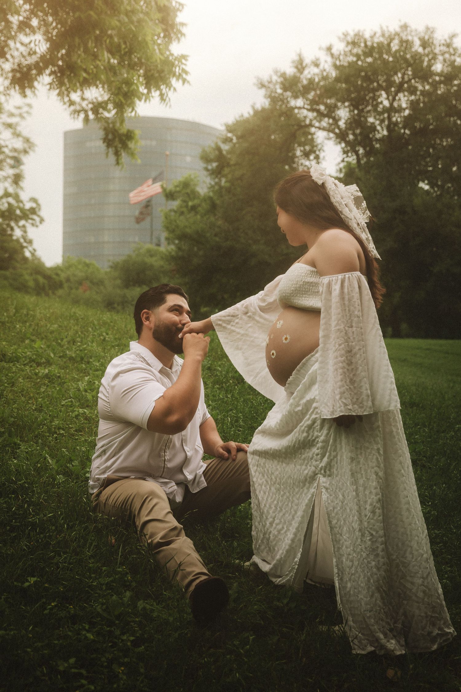 A couple in white clothing dances playfully together in a park during golden hour.
