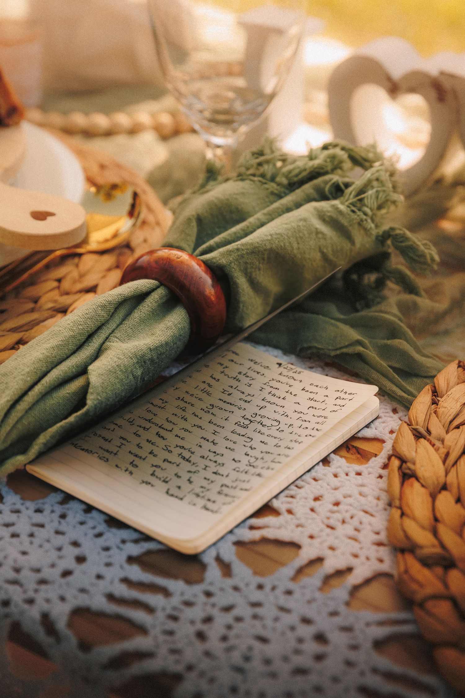 A handwritten letter on aged paper lies among scattered autumn leaves with a green fabric draped across the corner.