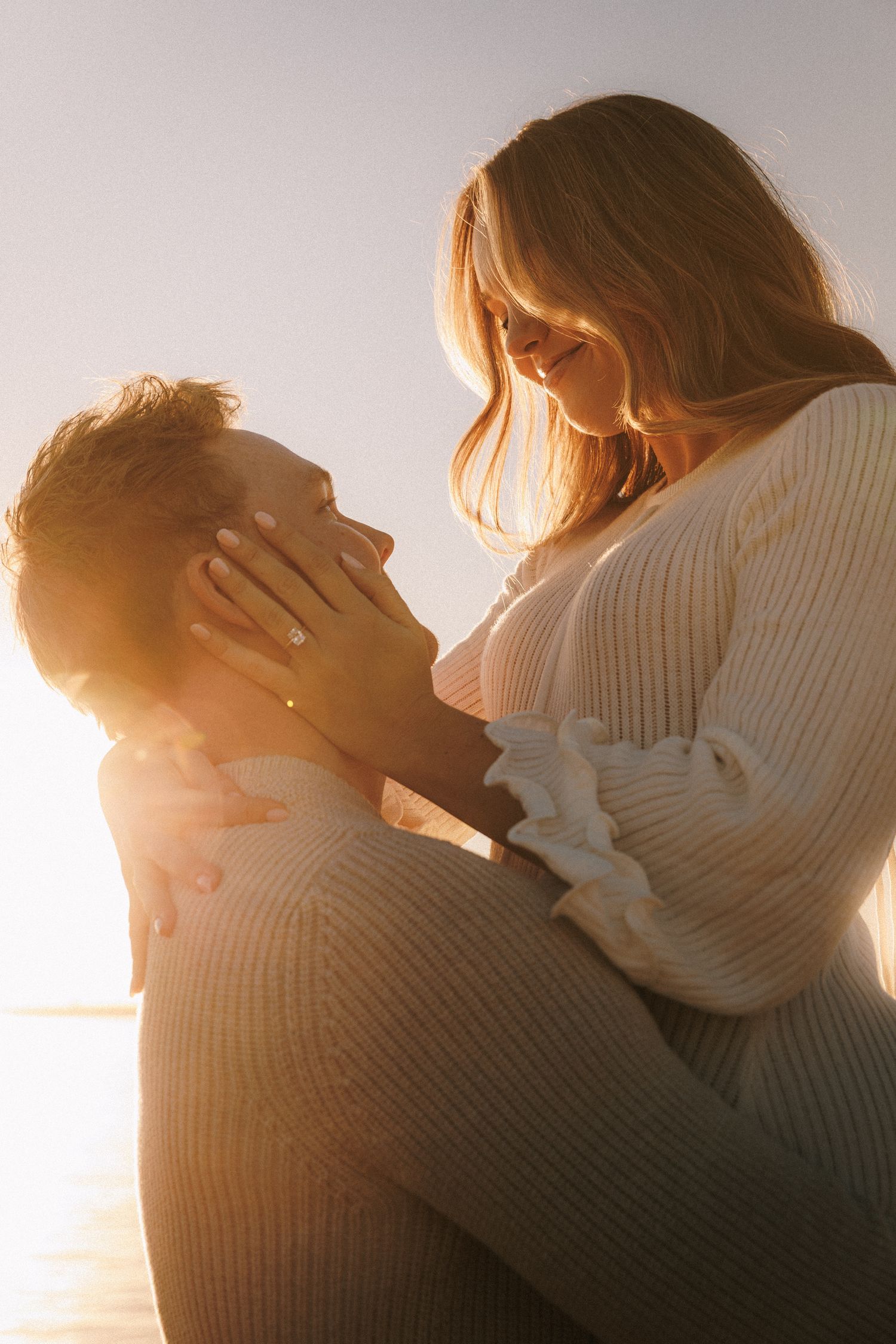 Intimate close-up silhouettes of a couple embracing in warm sunset light.