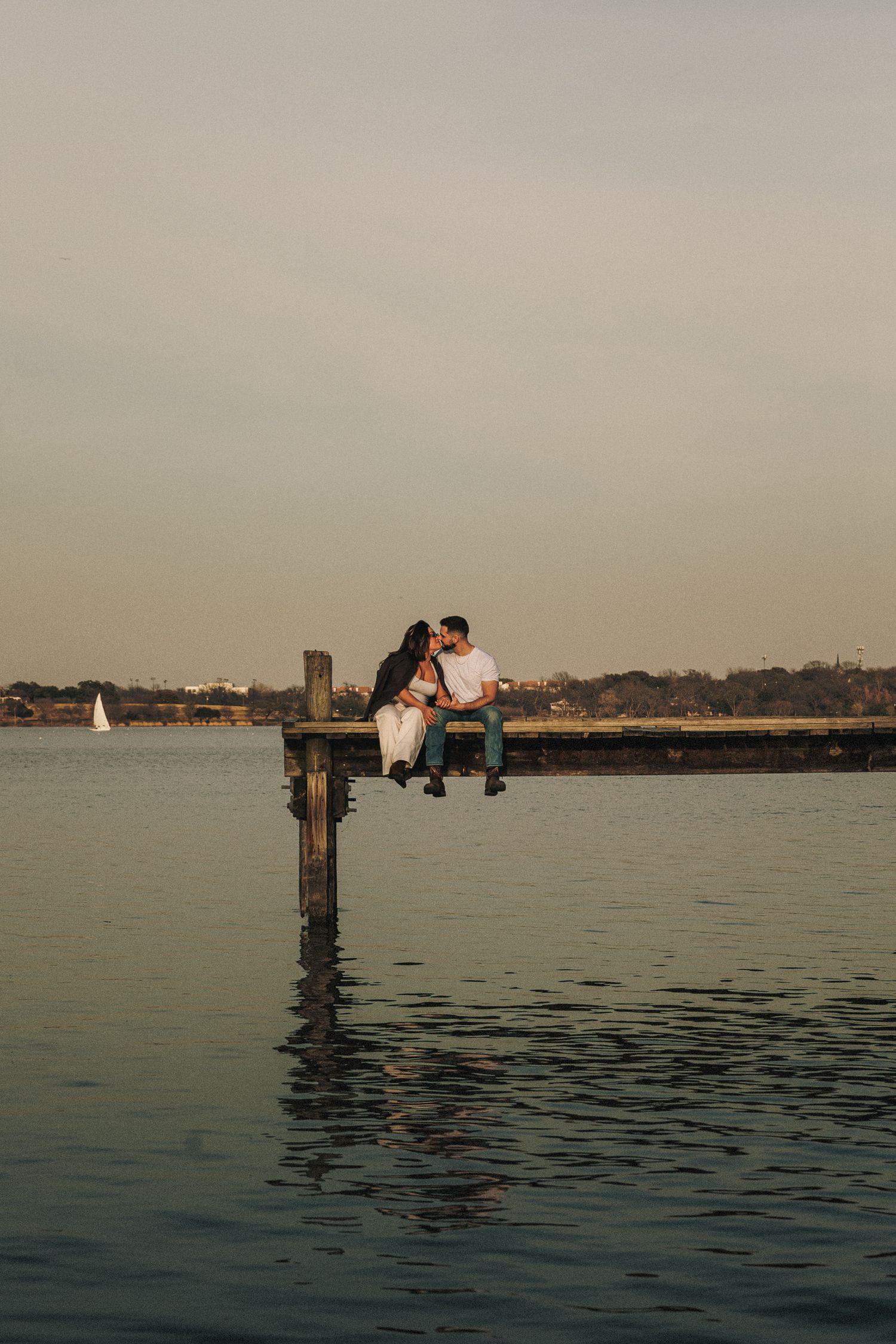 Romantic silhouettes on a dock against serene water and dusky sky.