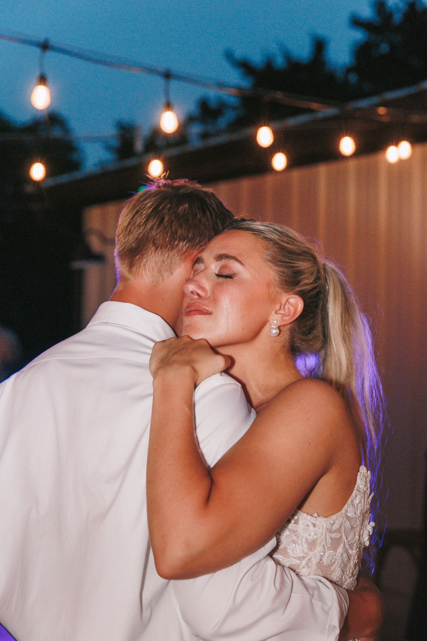 Evening wedding reception dance with string lights creating romantic ambiance.