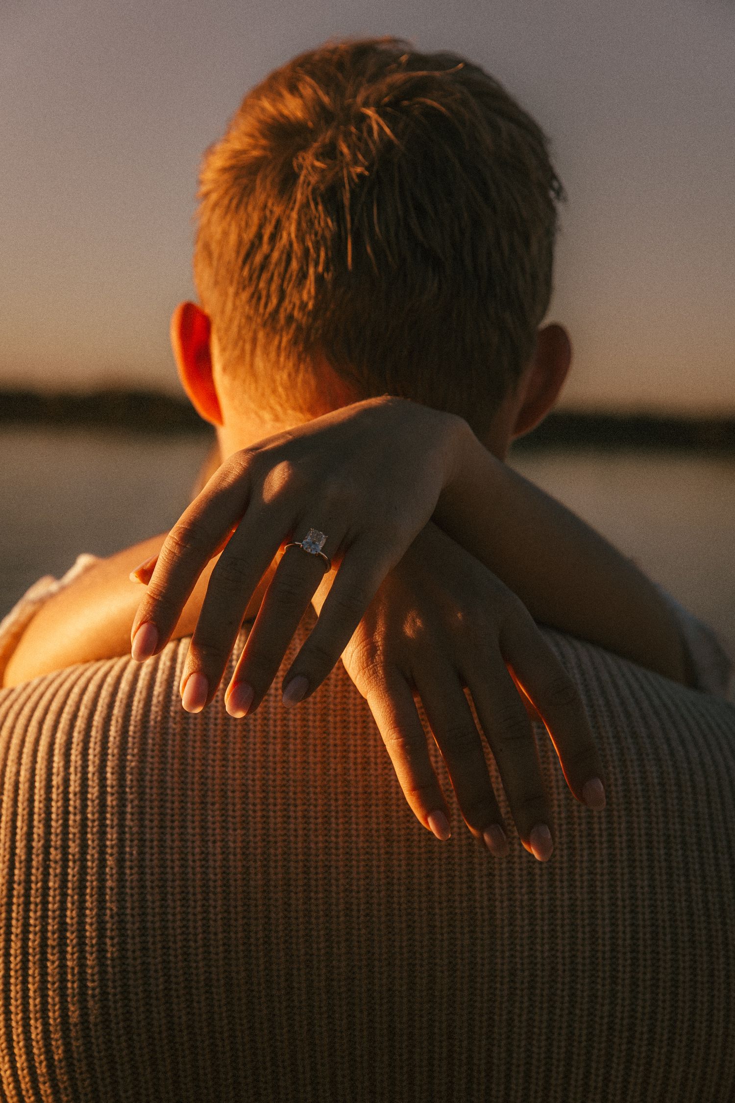 Close-up shot of hands resting on a gray knit sweater during golden hour sunset.