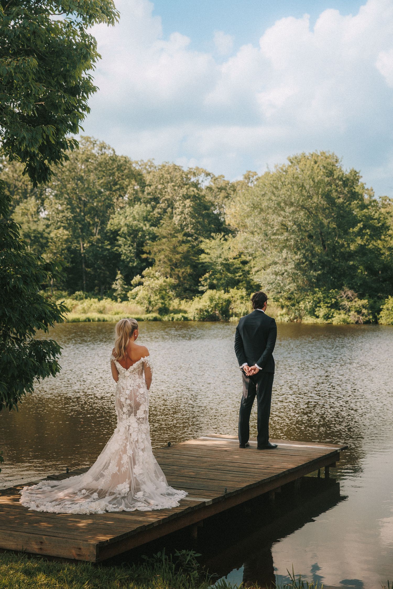 First look moment between couple on wooden dock over serene lake.