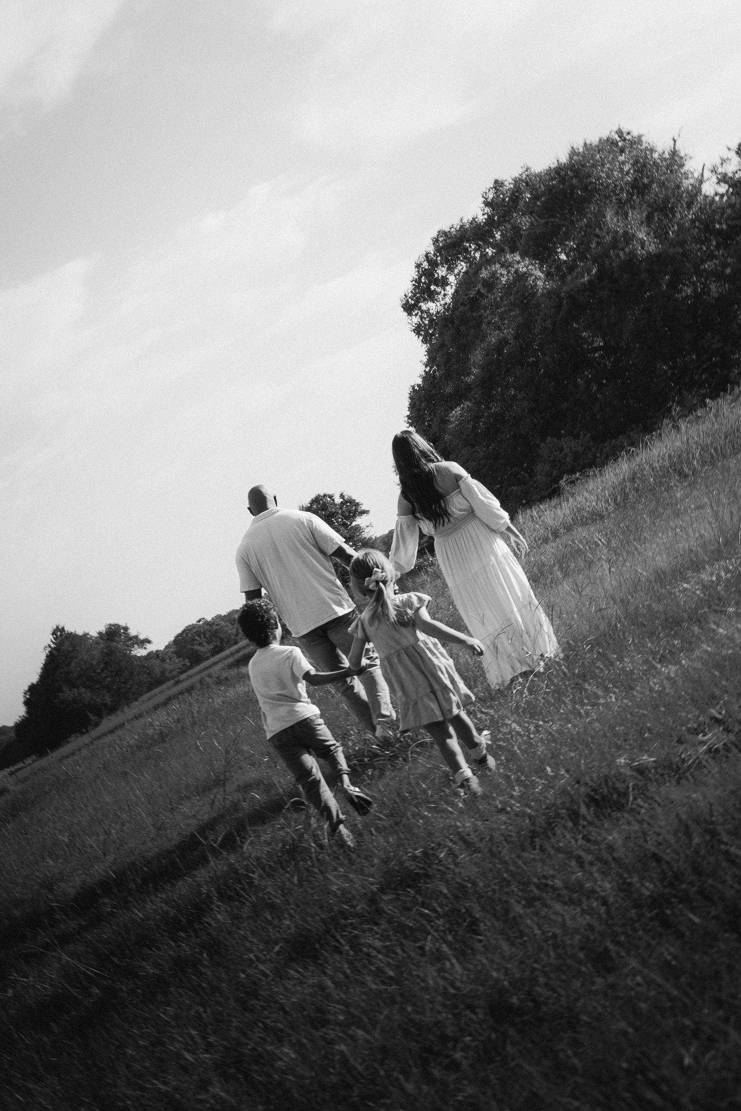 Black and white sequence shows people in white outfits running uphill through grassy terrain together.