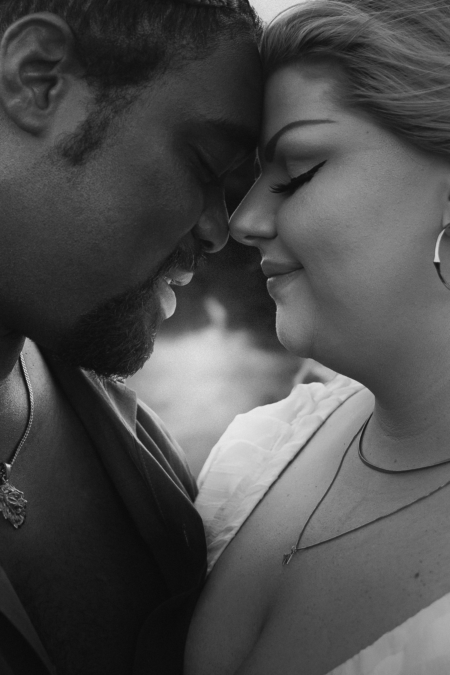 A tender black and white portrait capturing an intimate moment between a couple with their faces close together.