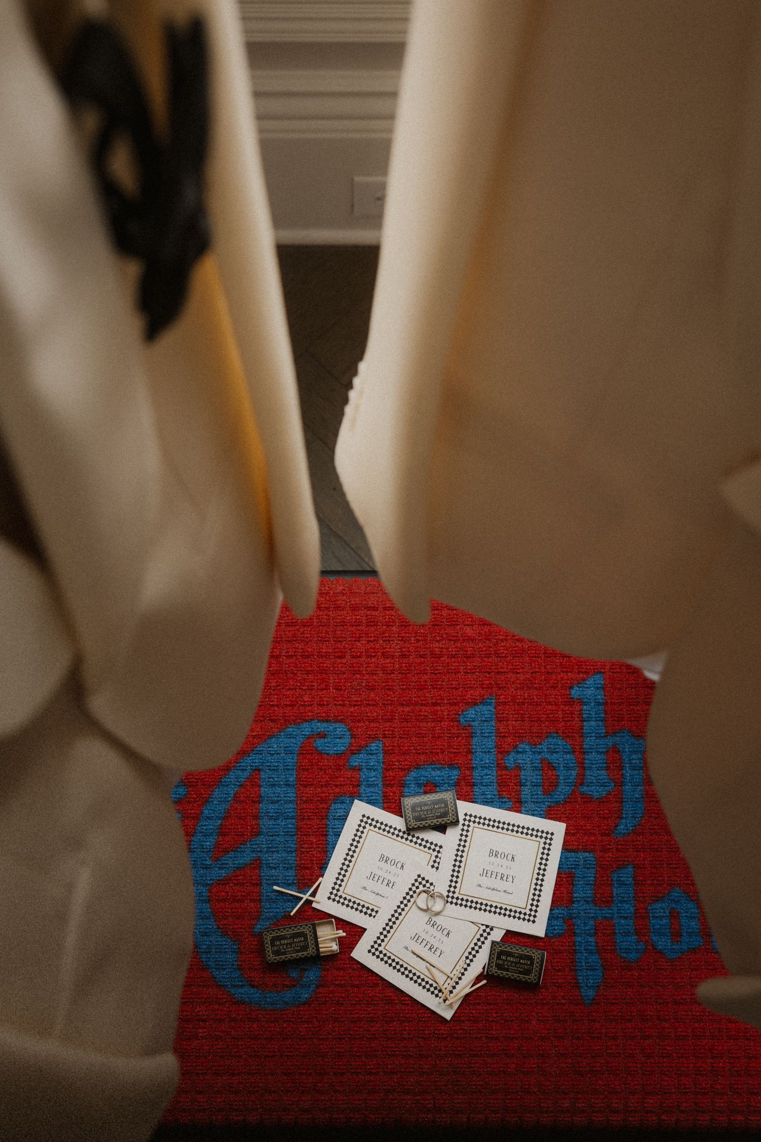 Red welcome mat with blue lettering and matchbooks at hotel entrance.