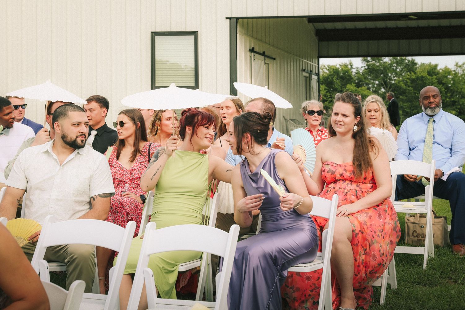 Wedding guests in colorful summer attire socialize at outdoor reception.
