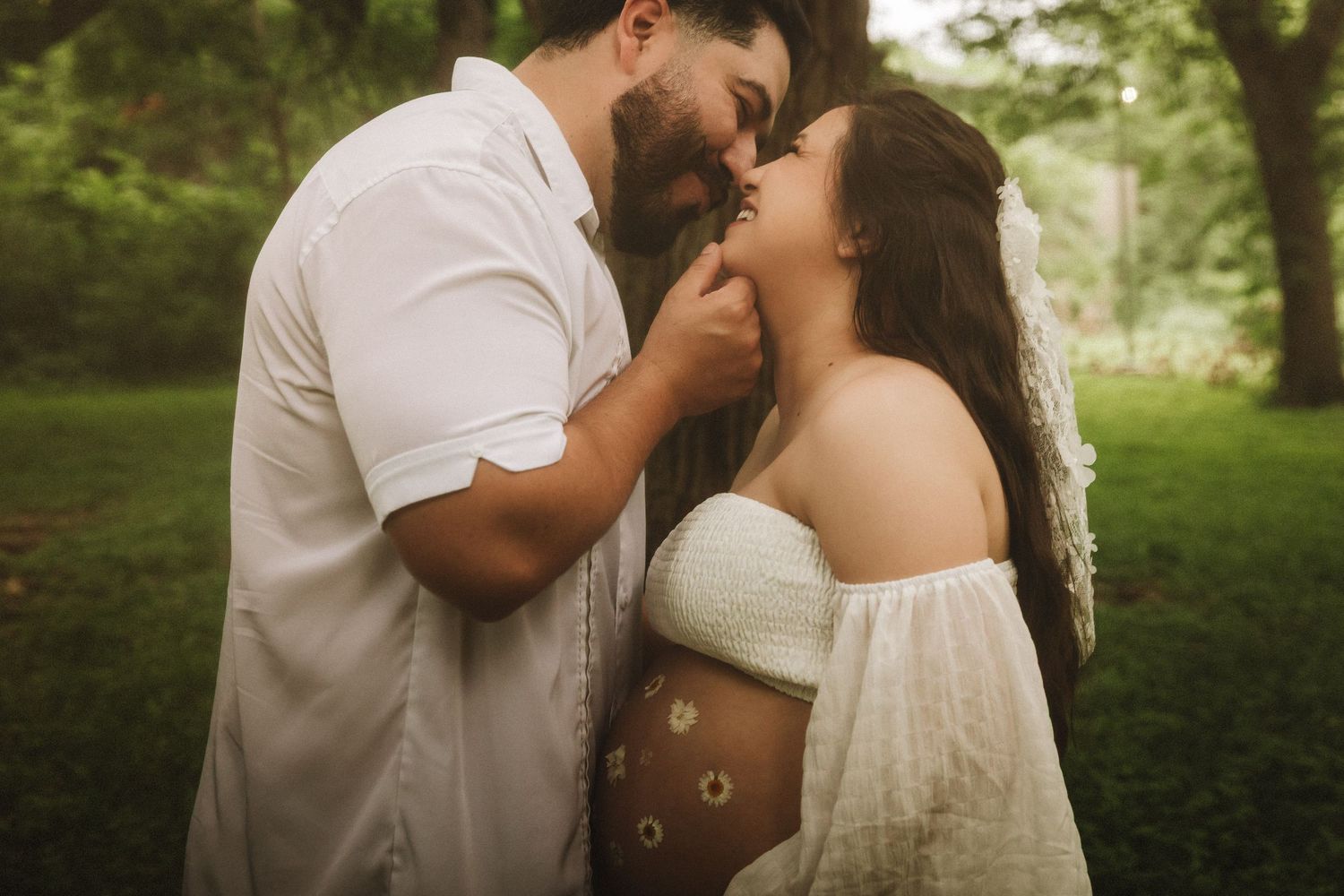 Romantic couple shares intimate wedding day kisses in lush green outdoor garden setting.