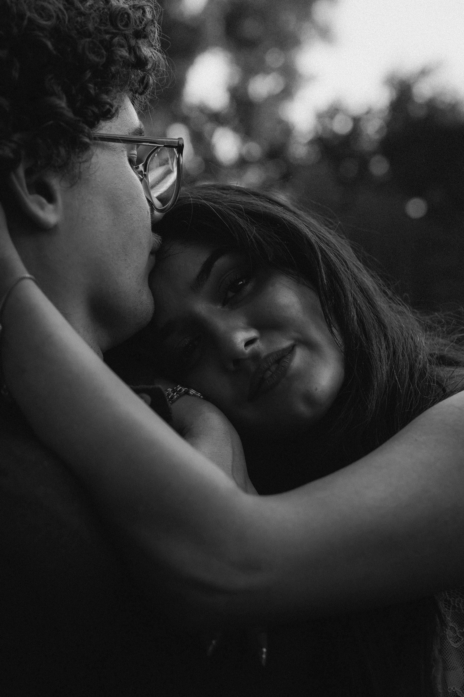 Black and white romantic portrait capturing intimate embrace between couple in soft natural lighting.