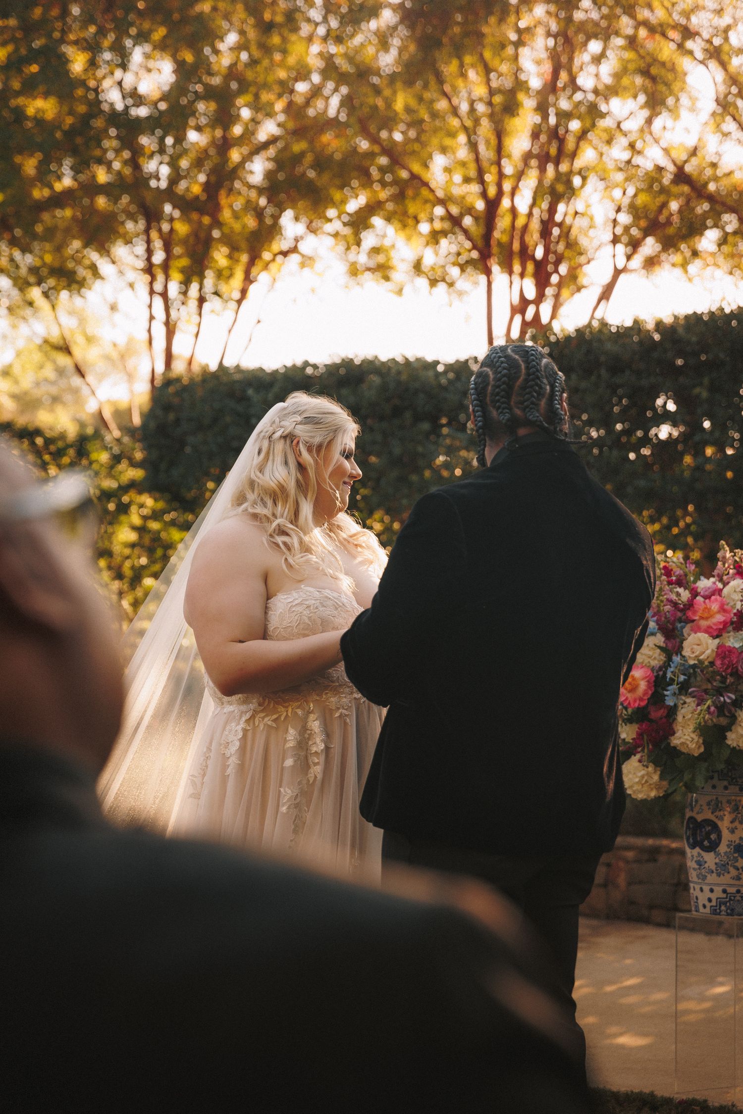 Bride and groom share an intimate moment at outdoor wedding ceremony surrounded by autumn trees.