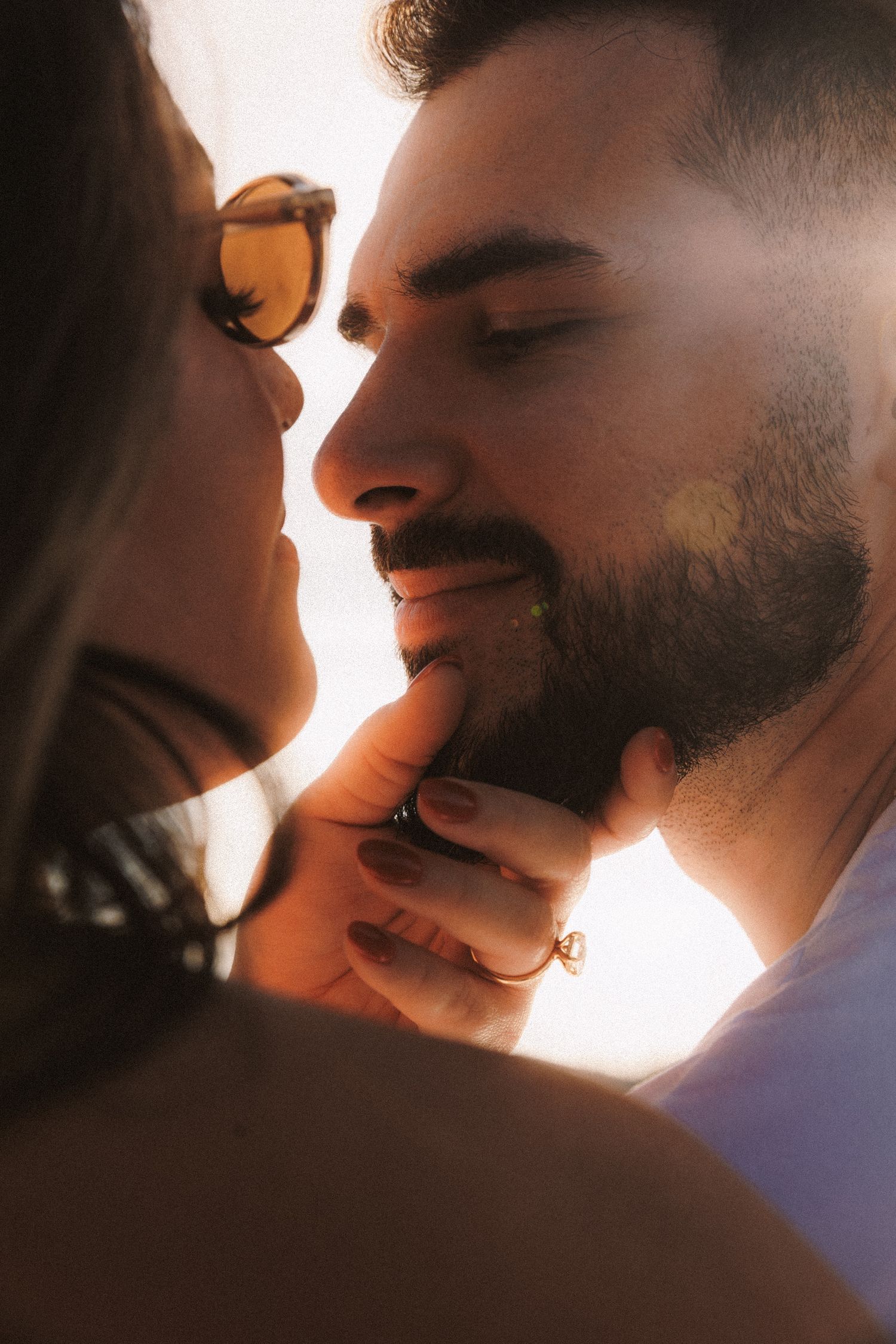 Close up silhouette of two faces about to kiss in warm sunset lighting.