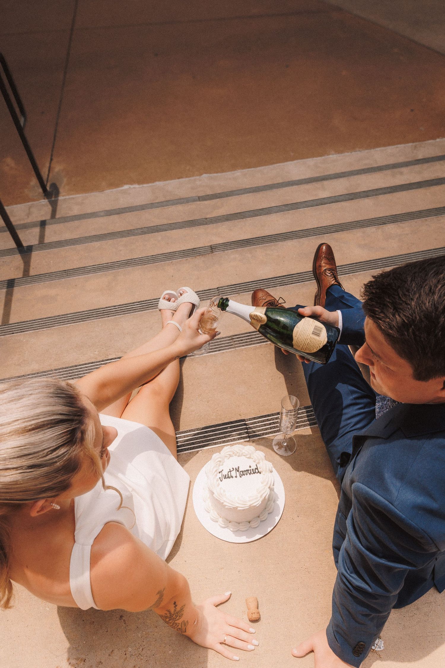 A sequence of people in white and blue outfits lying on a wooden floor reaching beneath what appears to be a cabinet.