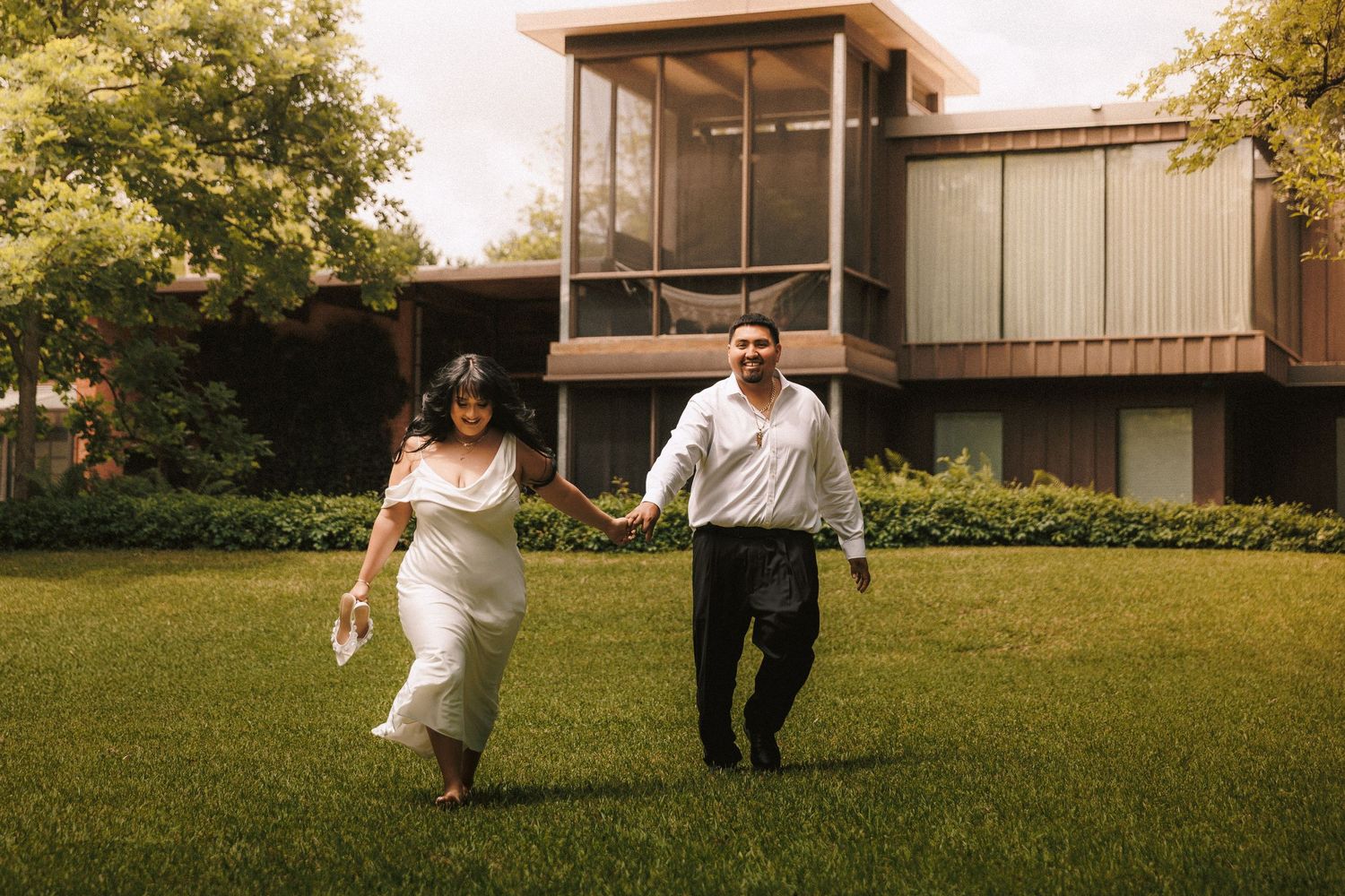 People enjoying outdoor activities at a backyard party with glass house architecture in summer.