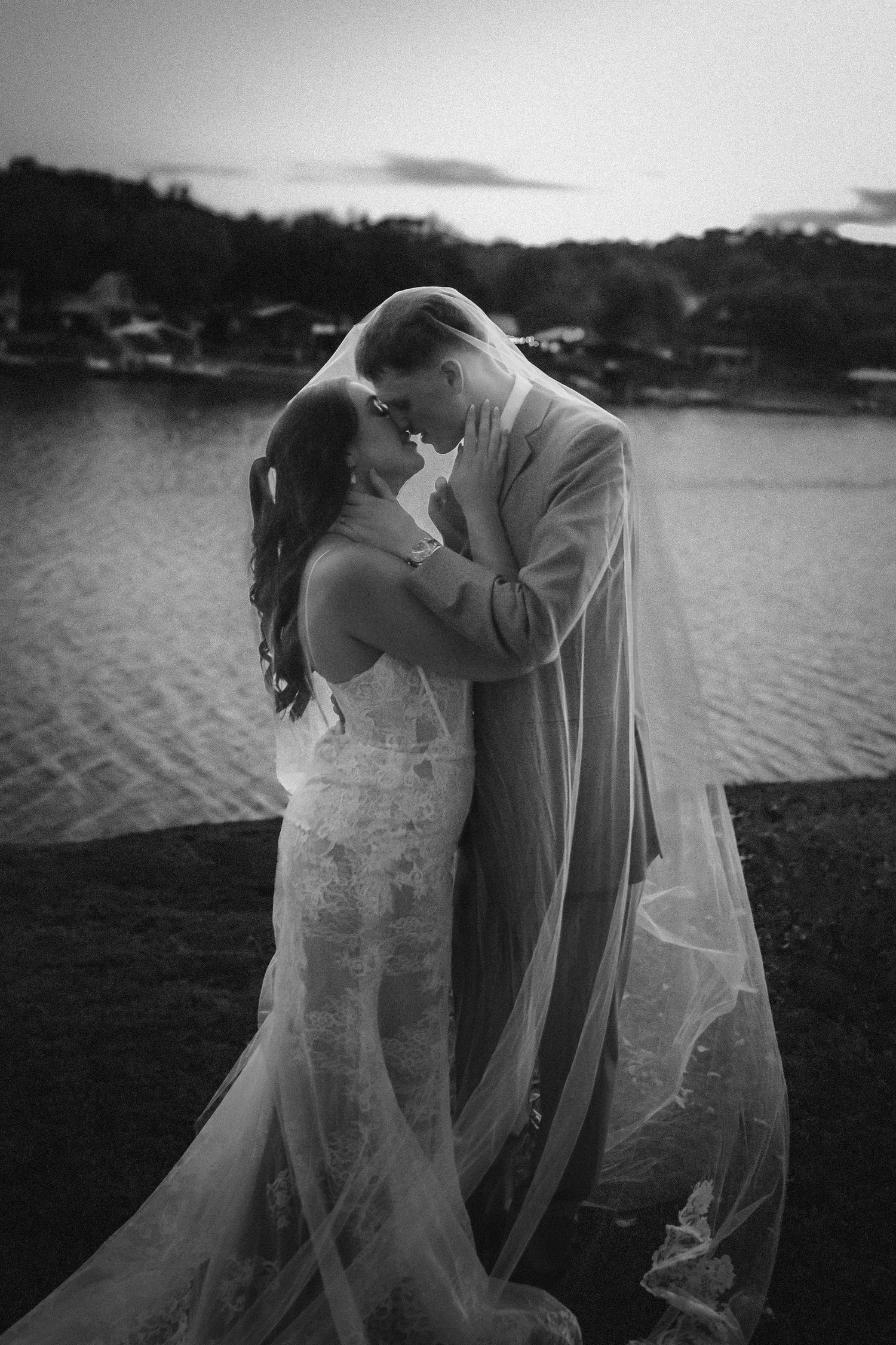 A romantic black and white wedding photo sequence showing an intimate couple's dip by a lake at sunset.