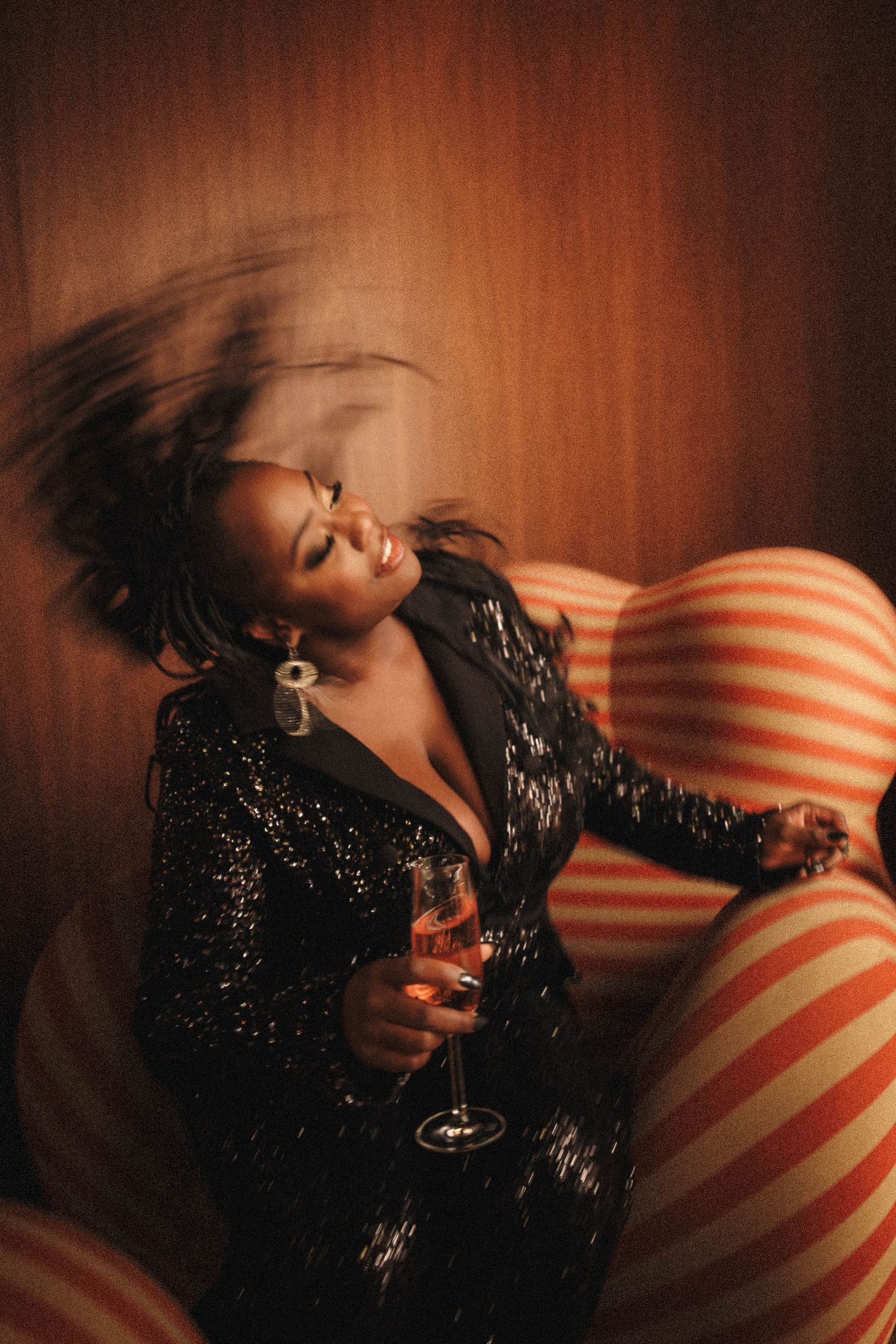 A person in a sparkly black top reclining on red and white striped pillows in a dimly lit setting creates a moody sequence.