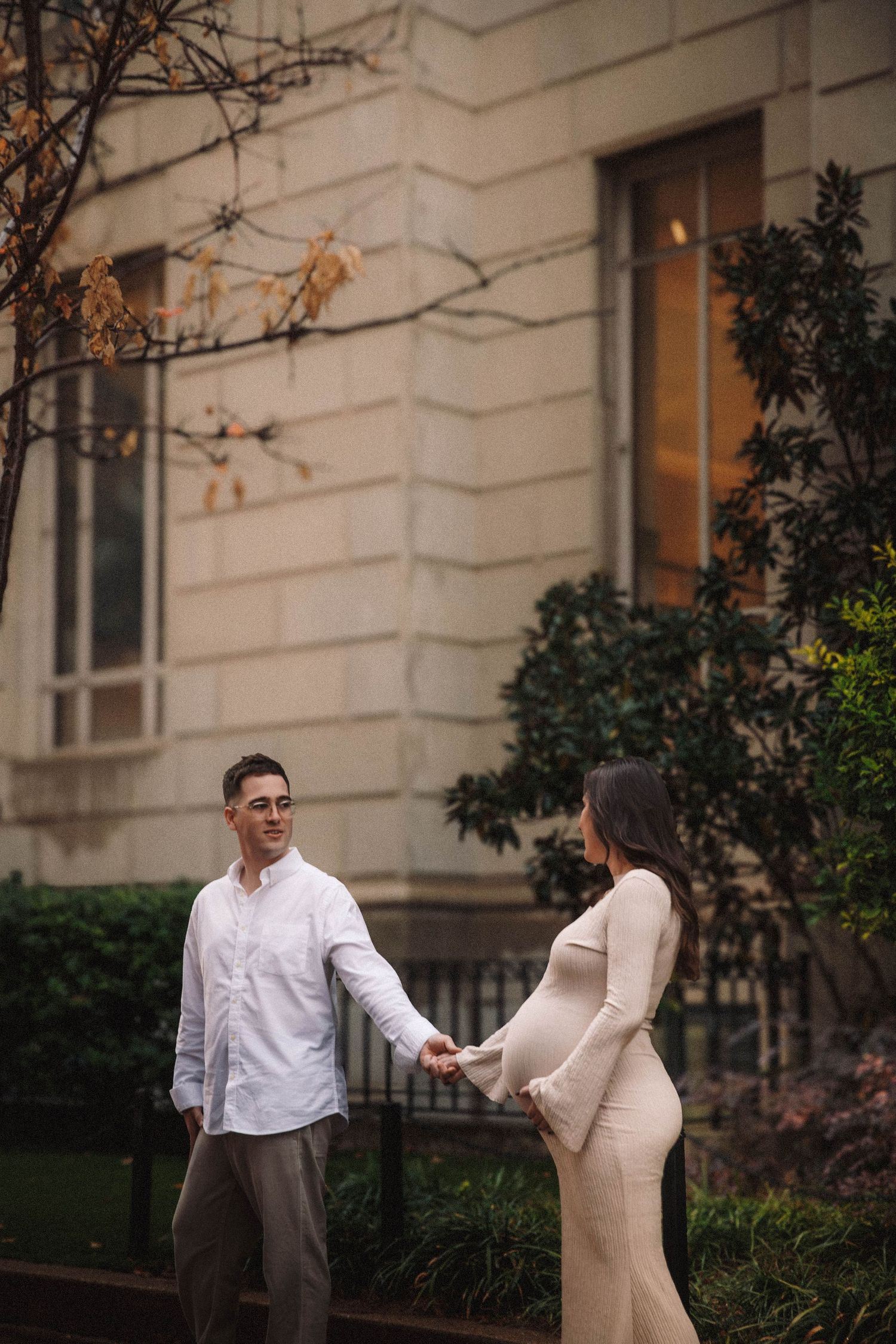 Professional lifestyle photography shows couple's joyful dance together outdoors by elegant building facade.