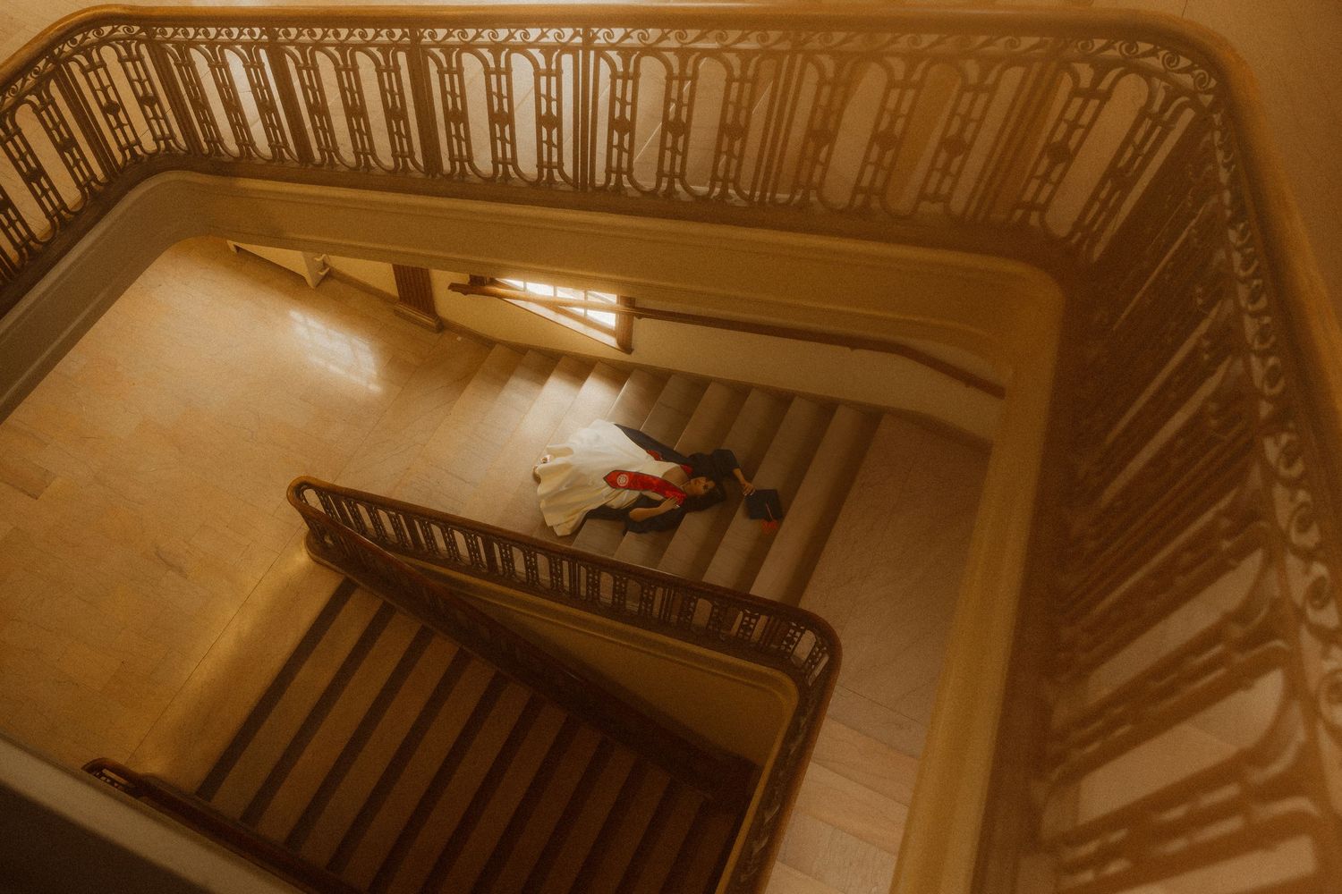 Aerial view of an elegant spiral staircase with ornate railings and a floral arrangement on the landing below.