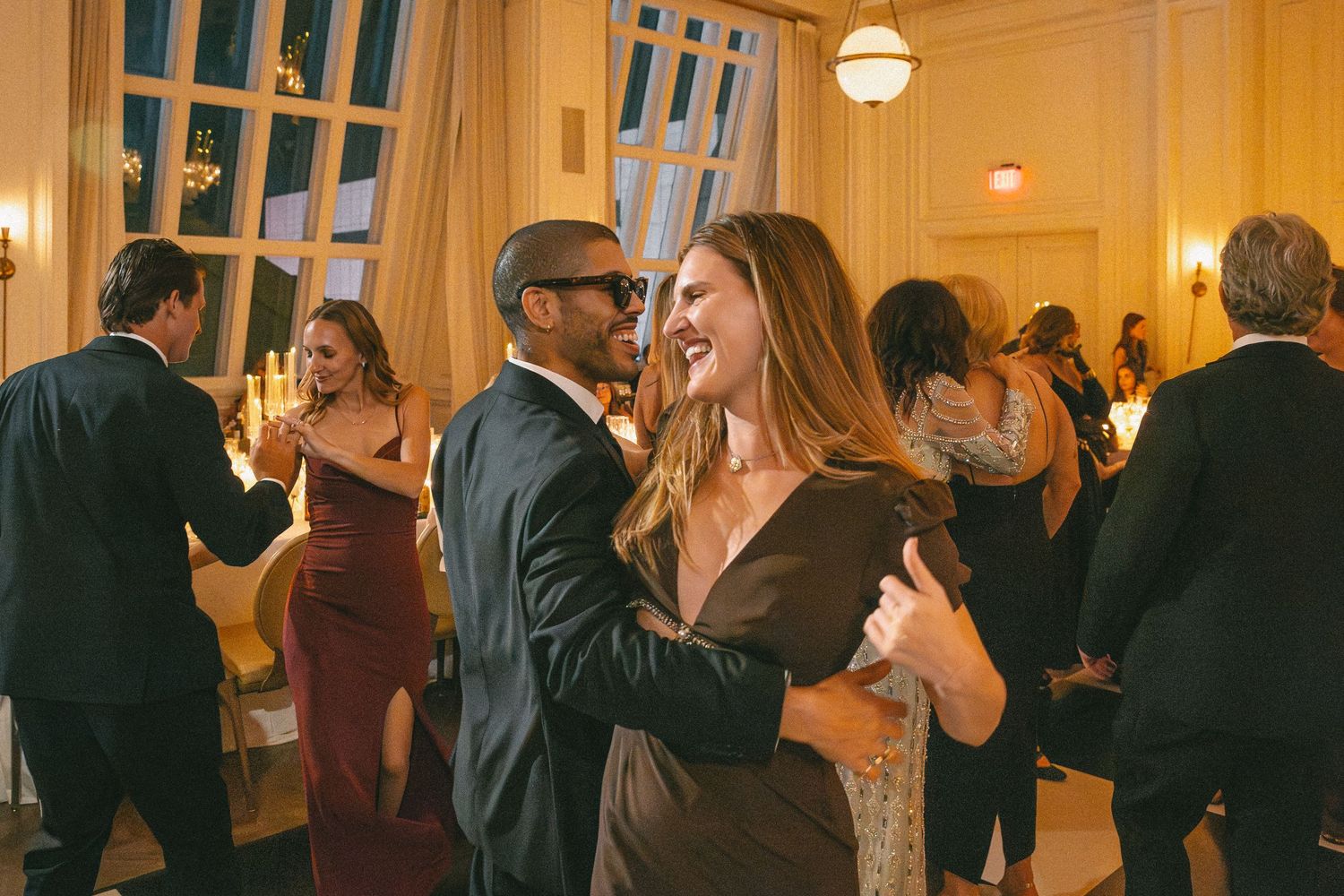 Couple dancing joyfully at elegant wedding reception with guests in background.