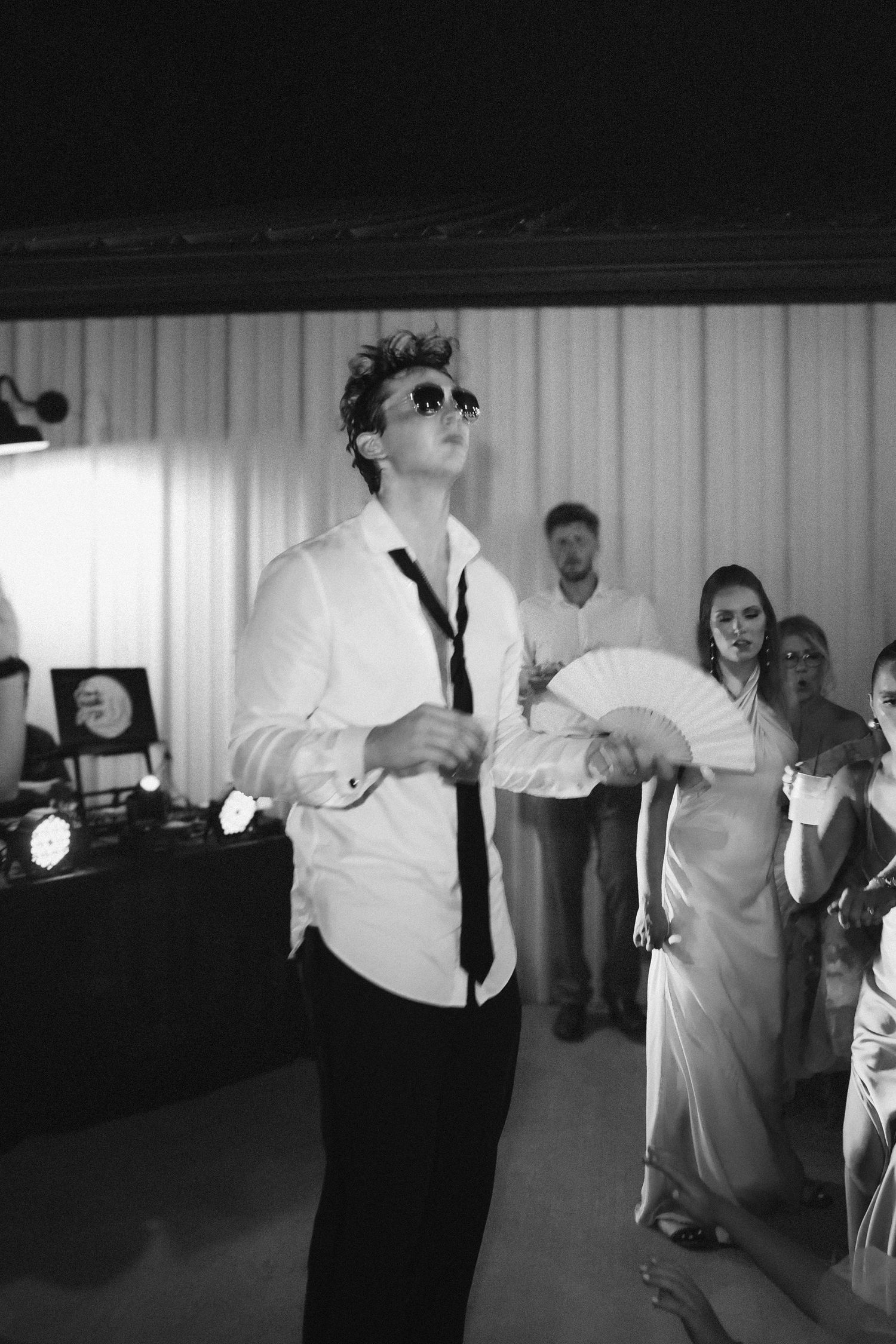 Wedding party members dance and celebrate in black and white on a reception dance floor.