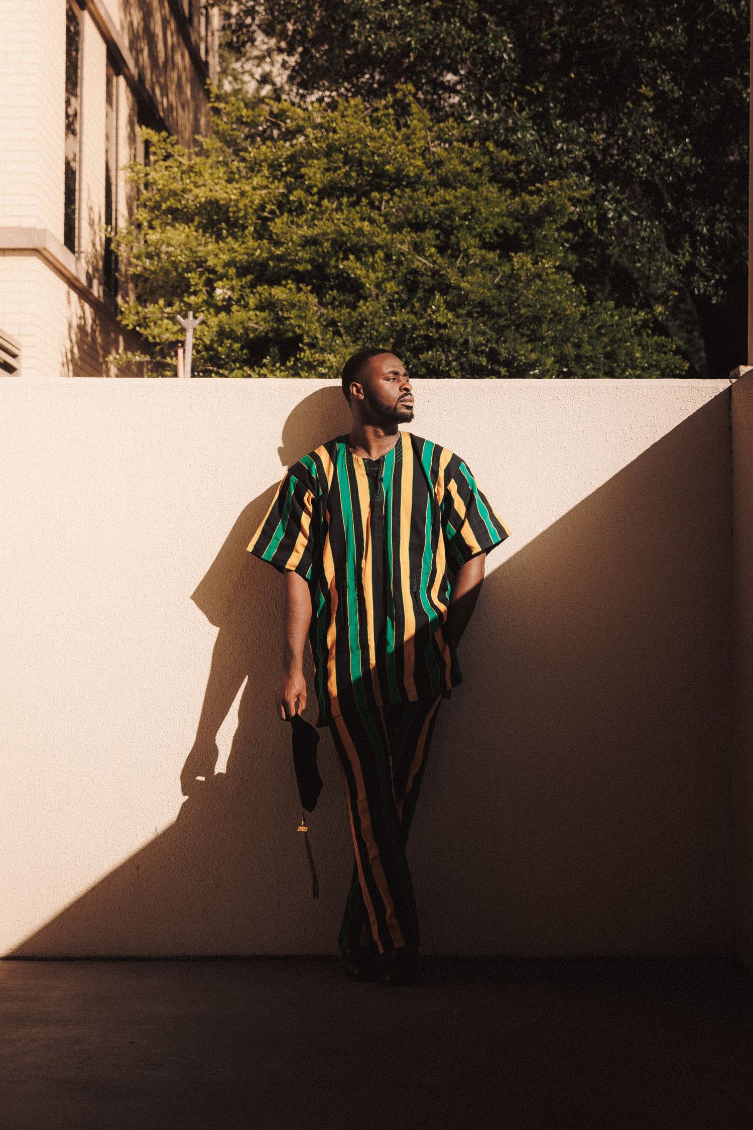 Person in striped green and black shirt lounging on white ledge in dramatic sunlight and shadow.