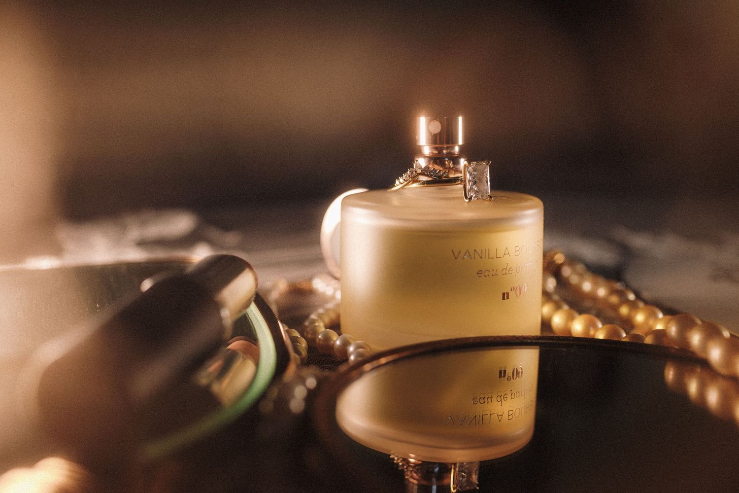 Close-up of a luxury perfume bottle with golden warm lighting and pearl necklace in background.