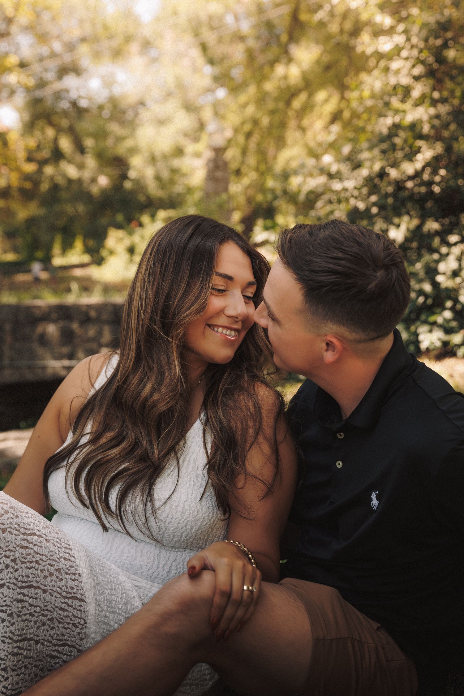 Romantic couple shares intimate moments in a sunlit outdoor setting with bokeh and natural lighting effects.
