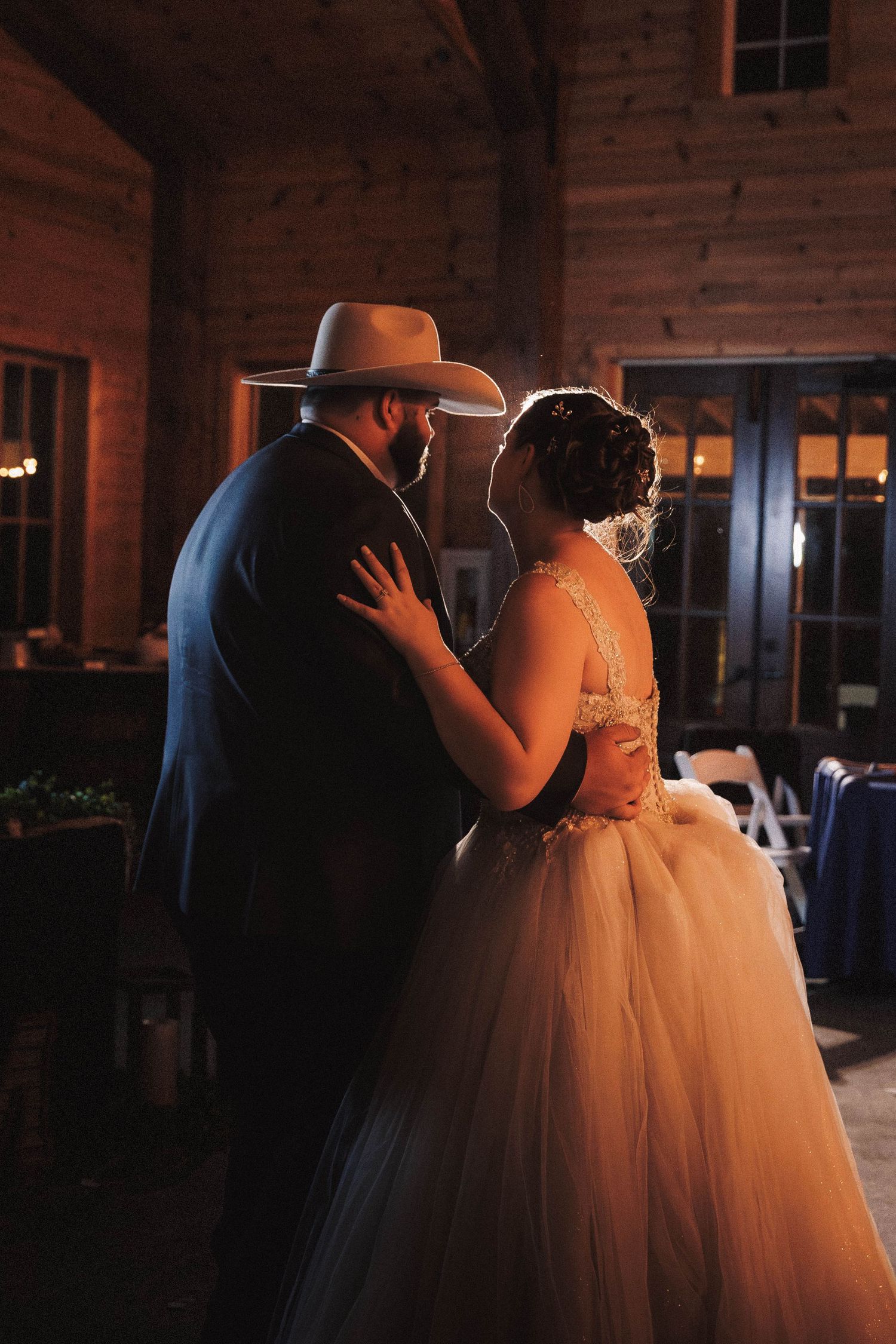 A couple share an intimate dance moment in a rustic barn venue during their country wedding.