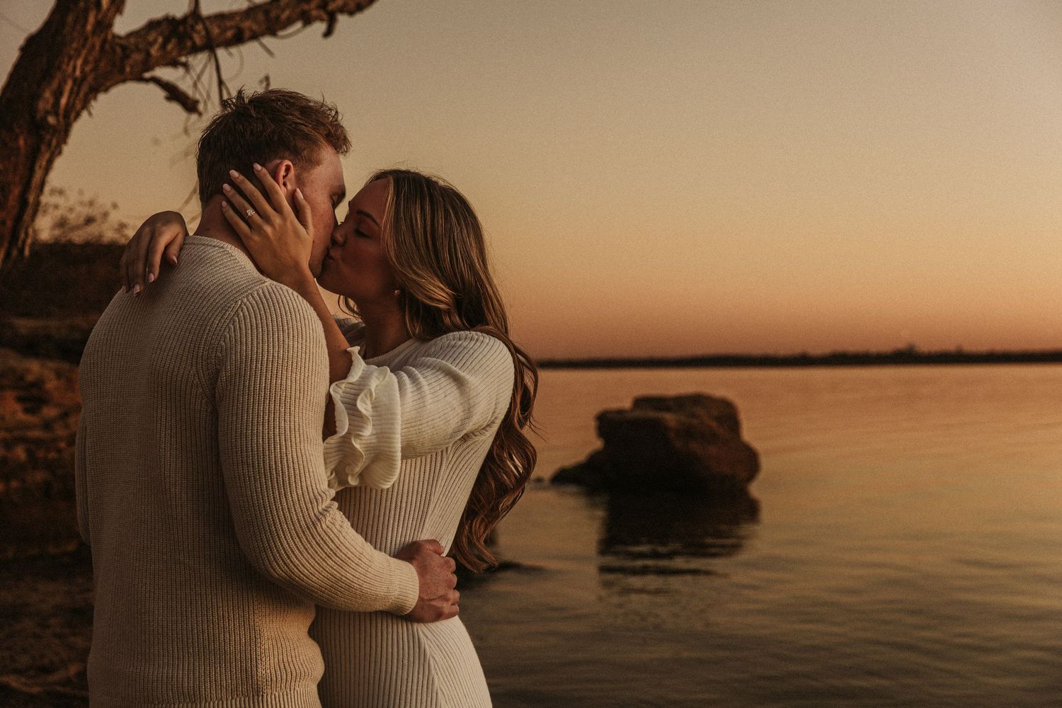 Romantic sunset photoshoot on rocky waterfront.
