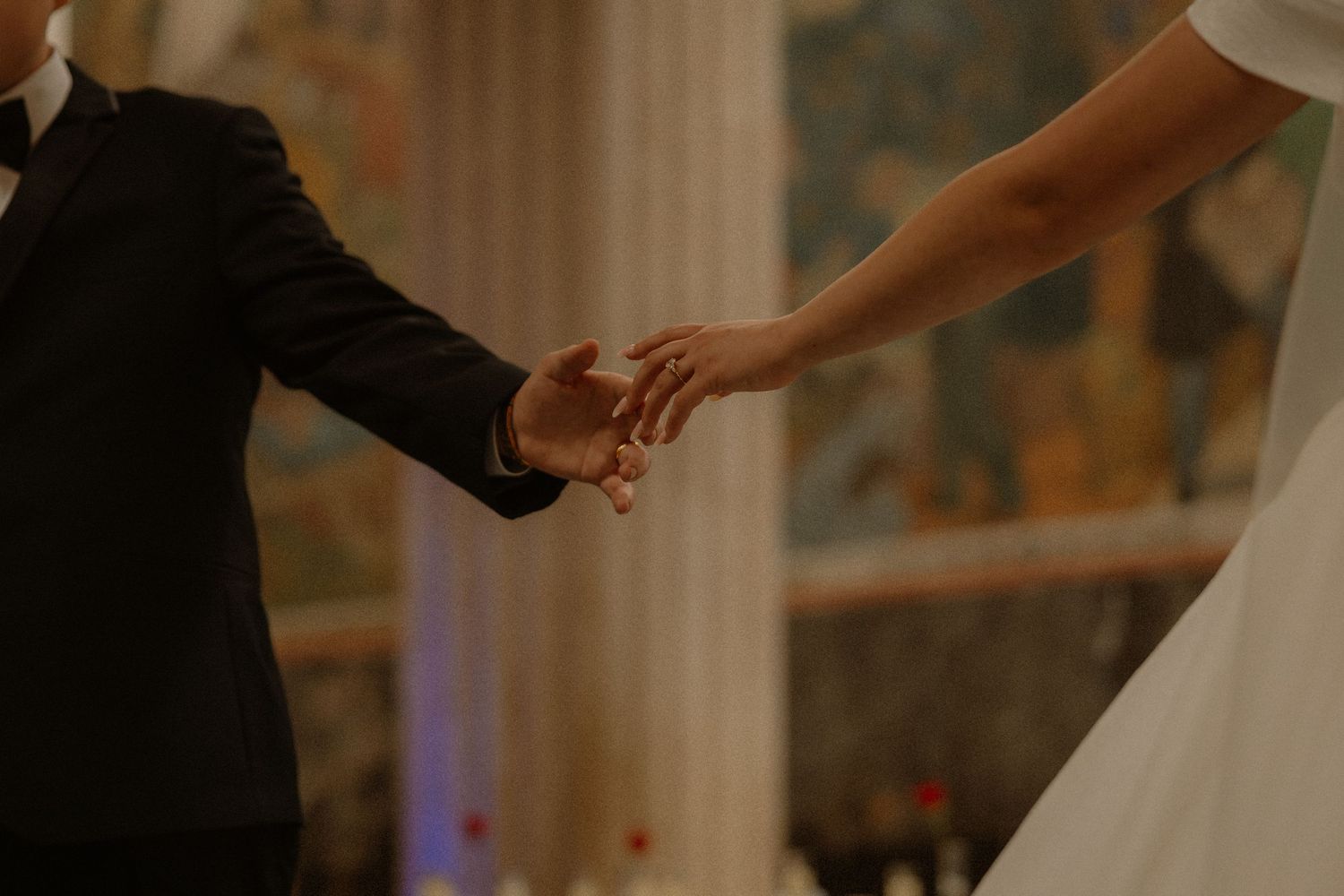 Bride and groom holding hands during first dance at elegantly decorated wedding reception venue.