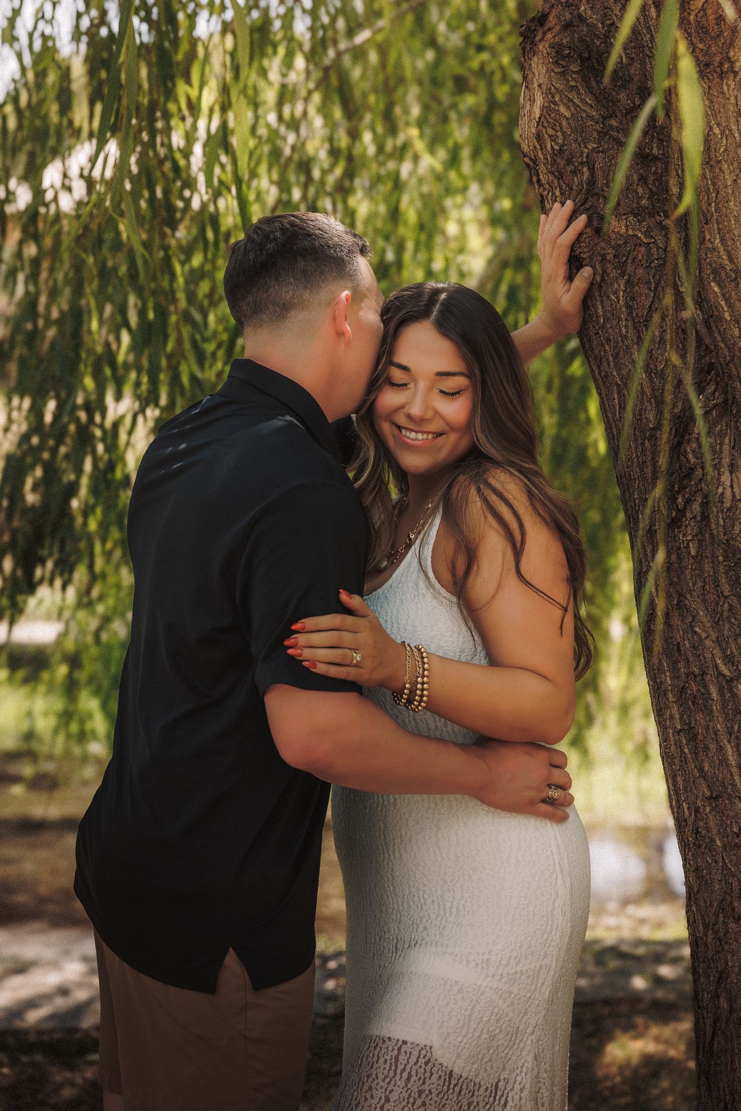 A romantic couple shares tender moments in a series of four intimate photos under a willow tree.