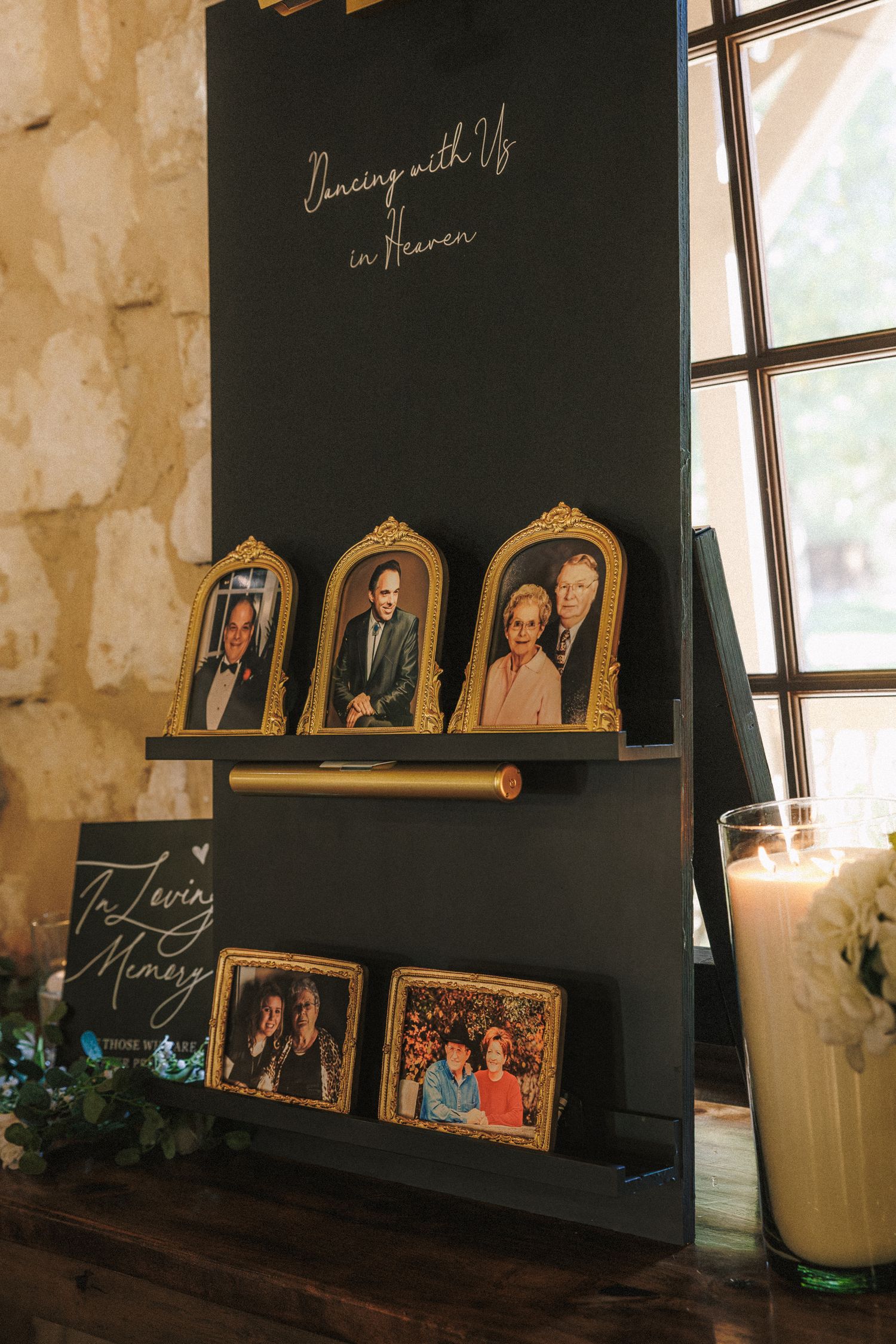 Wedding memorial display with framed photos in gold frames on black easel reading Dancing With Us in Heaven.