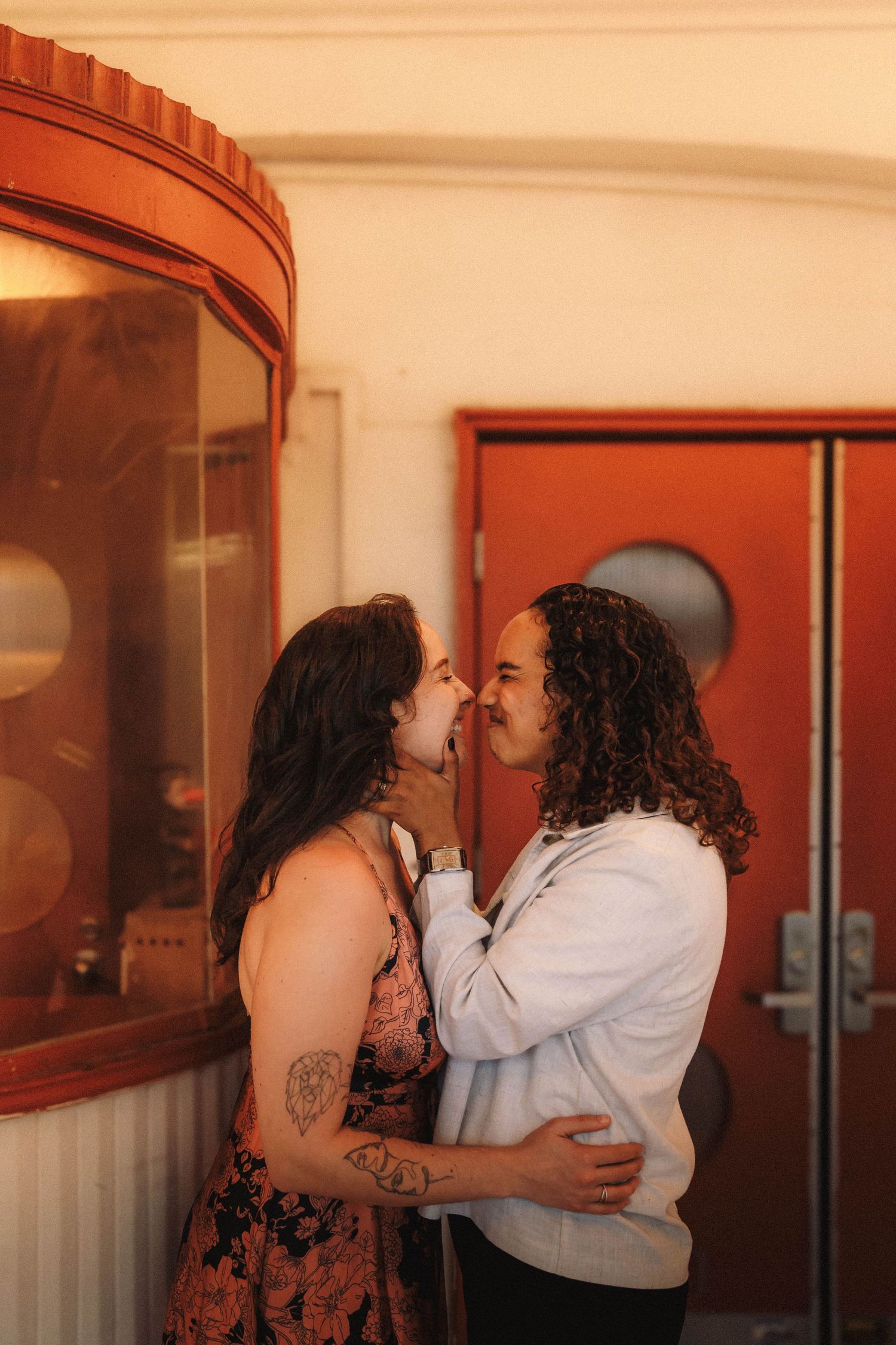 Two women embrace and share an intimate moment outside a vintage theater at golden hour.