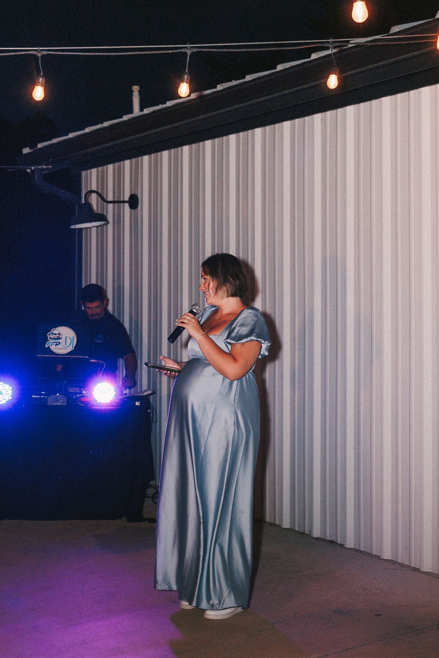 Wedding attendants in matching blue dresses perform on a stage under theatrical lighting.