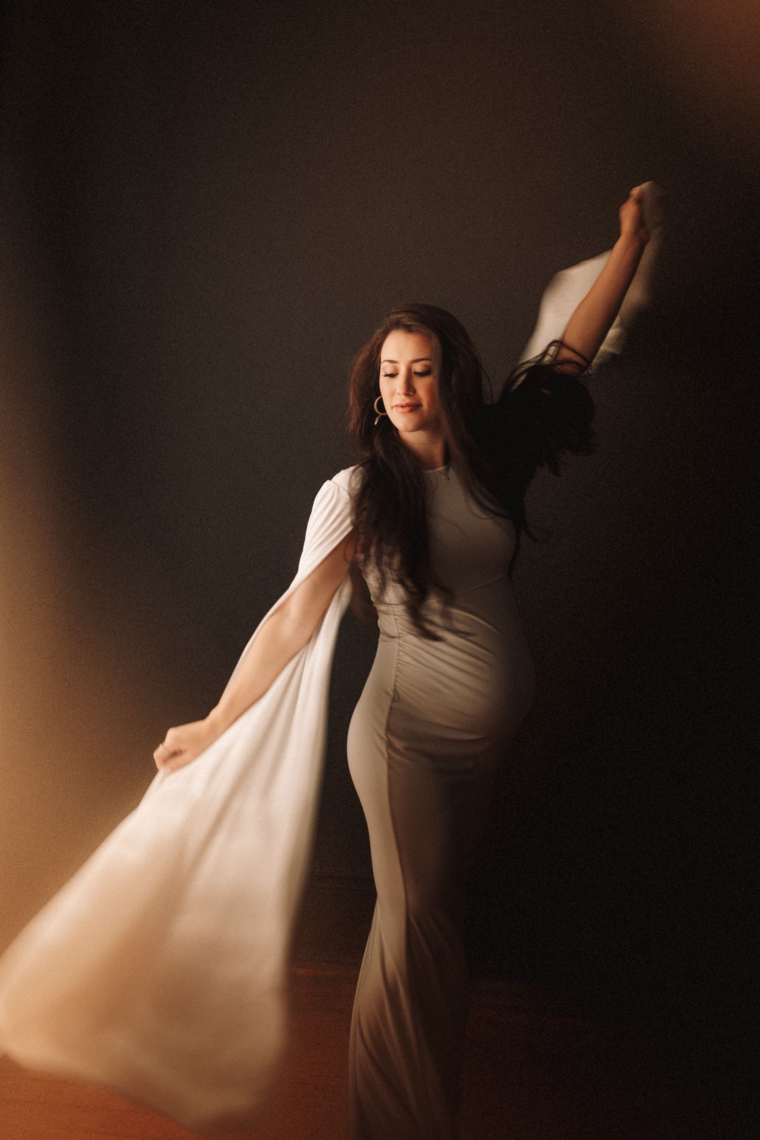 A graceful dance performance with flowing white fabric creating ethereal movement against a dark background.