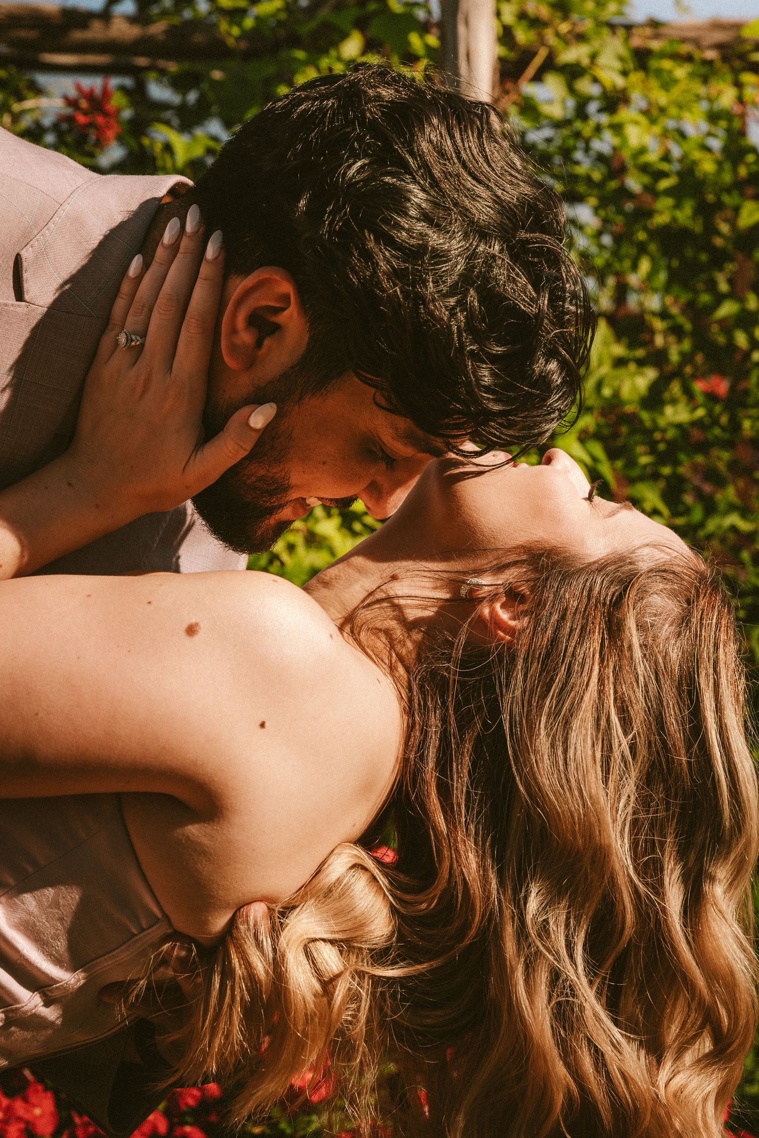 Romantic couple sharing intimate moments in a garden setting during golden hour.
