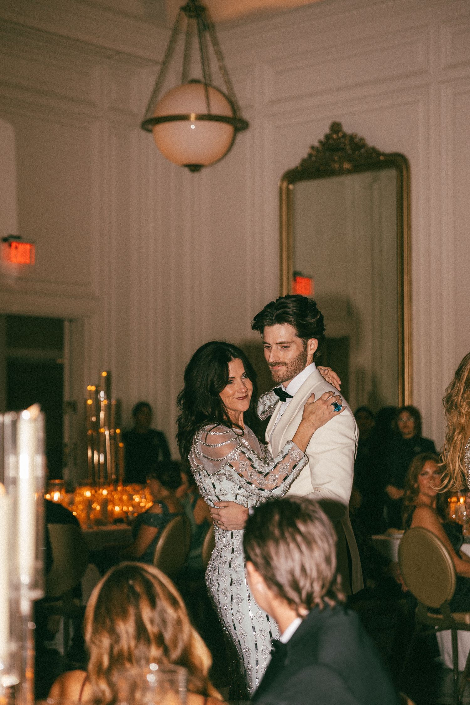 A couple shares a romantic first dance in an elegant candlelit wedding reception ballroom.