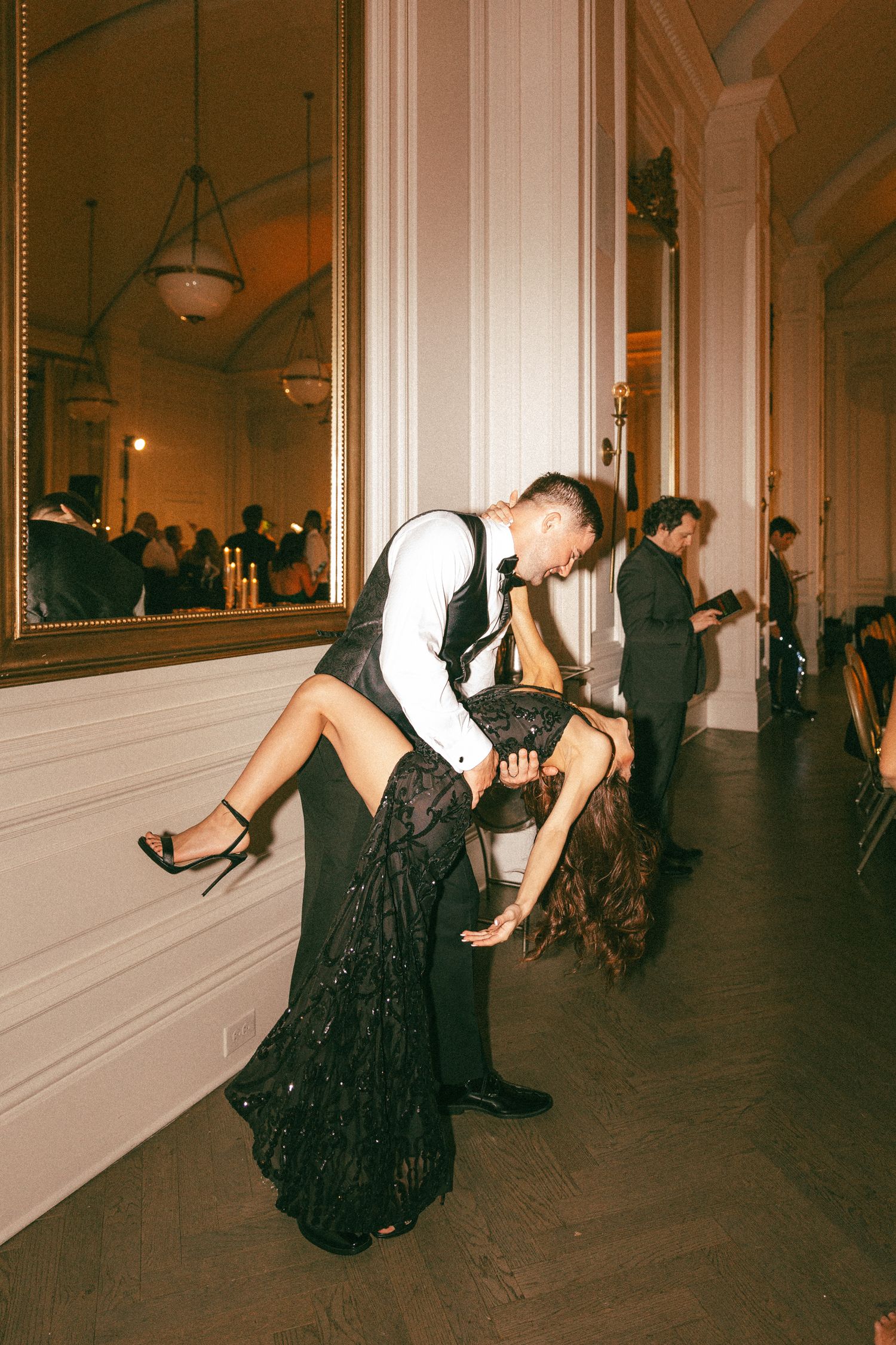 Couple performs dramatic dip dance move at elegant wedding reception.