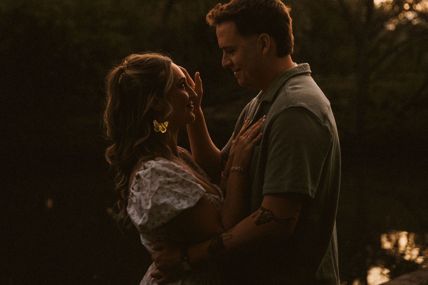 Couple sharing a romantic moment at golden hour, facing each other tenderly in warm sunset light outdoors.
