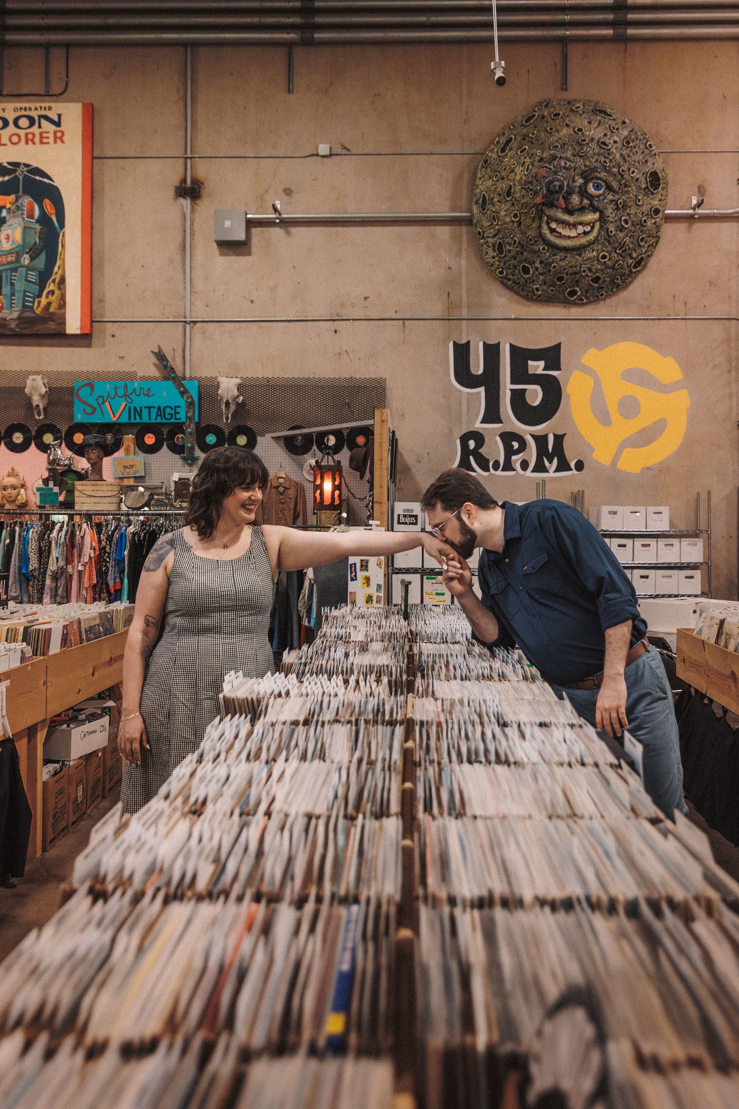 Vinyl record store interior with tall wooden bins filled with albums and shoppers browsing through the collection.