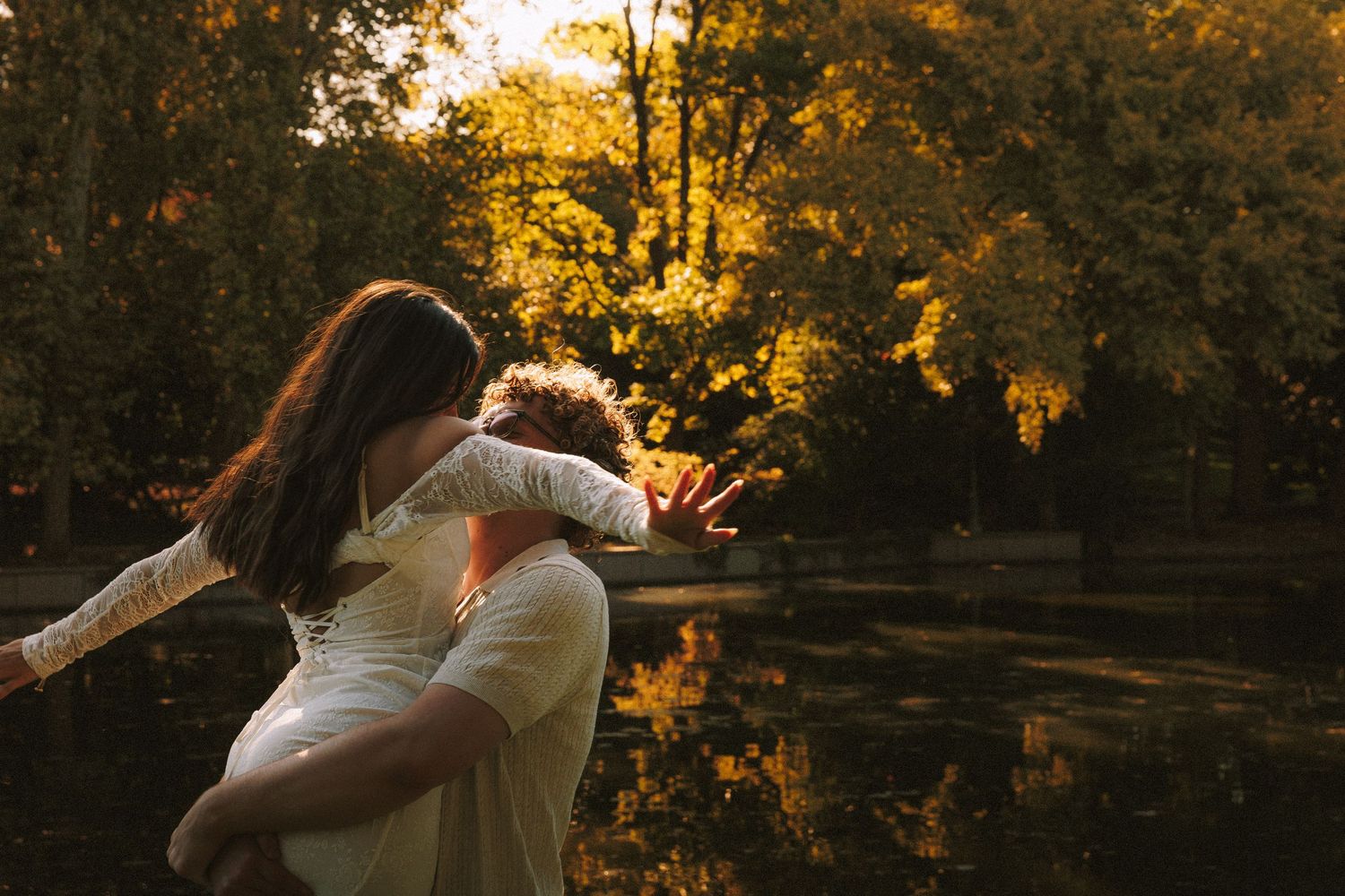 A playful piggyback ride moment captured against a sunset-lit pond.