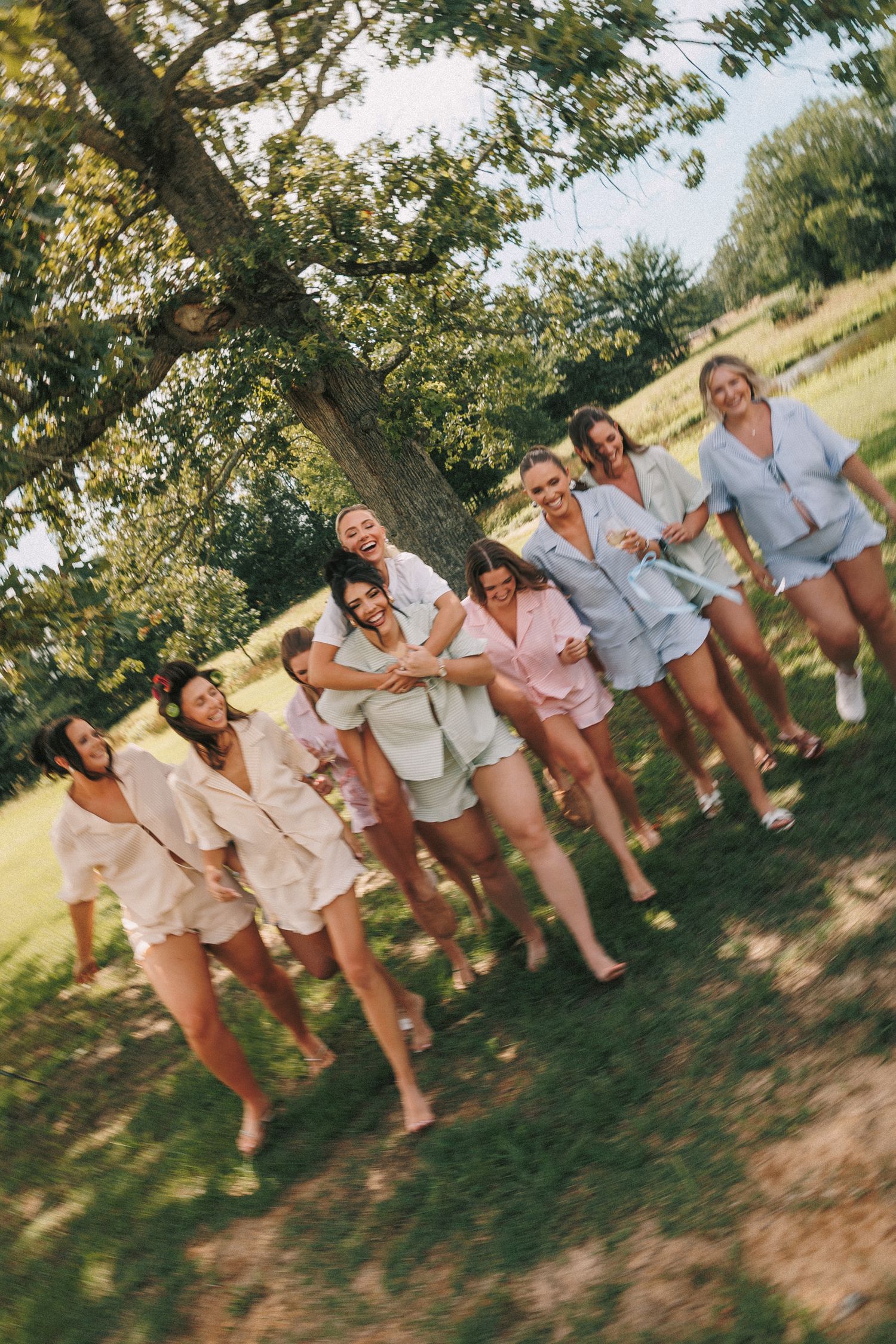 Wedding party in casual white and beige outfits posing playfully together outdoors.