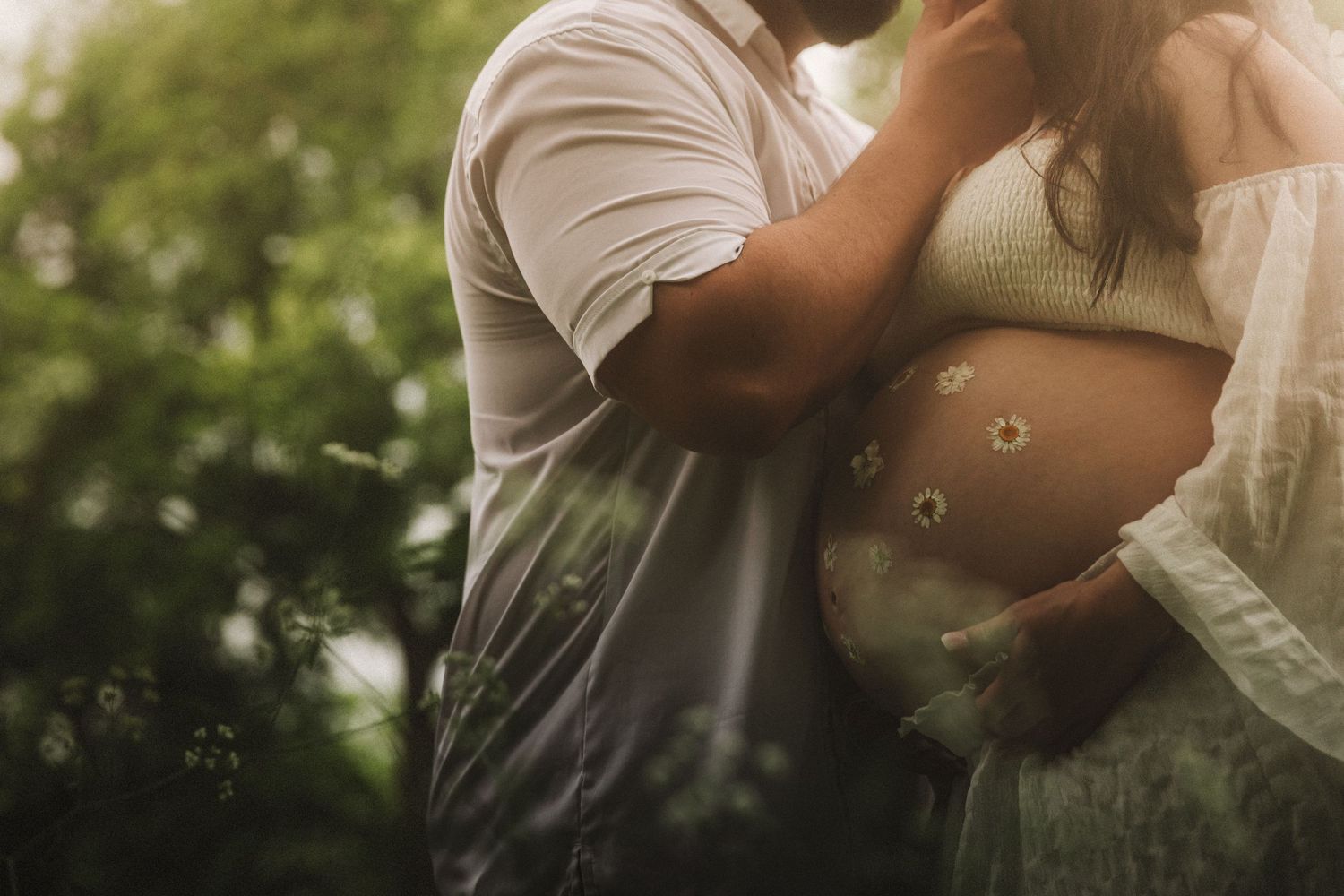 A romantic couple shares an intimate kiss in a sunlit garden setting with soft bokeh lighting effects.