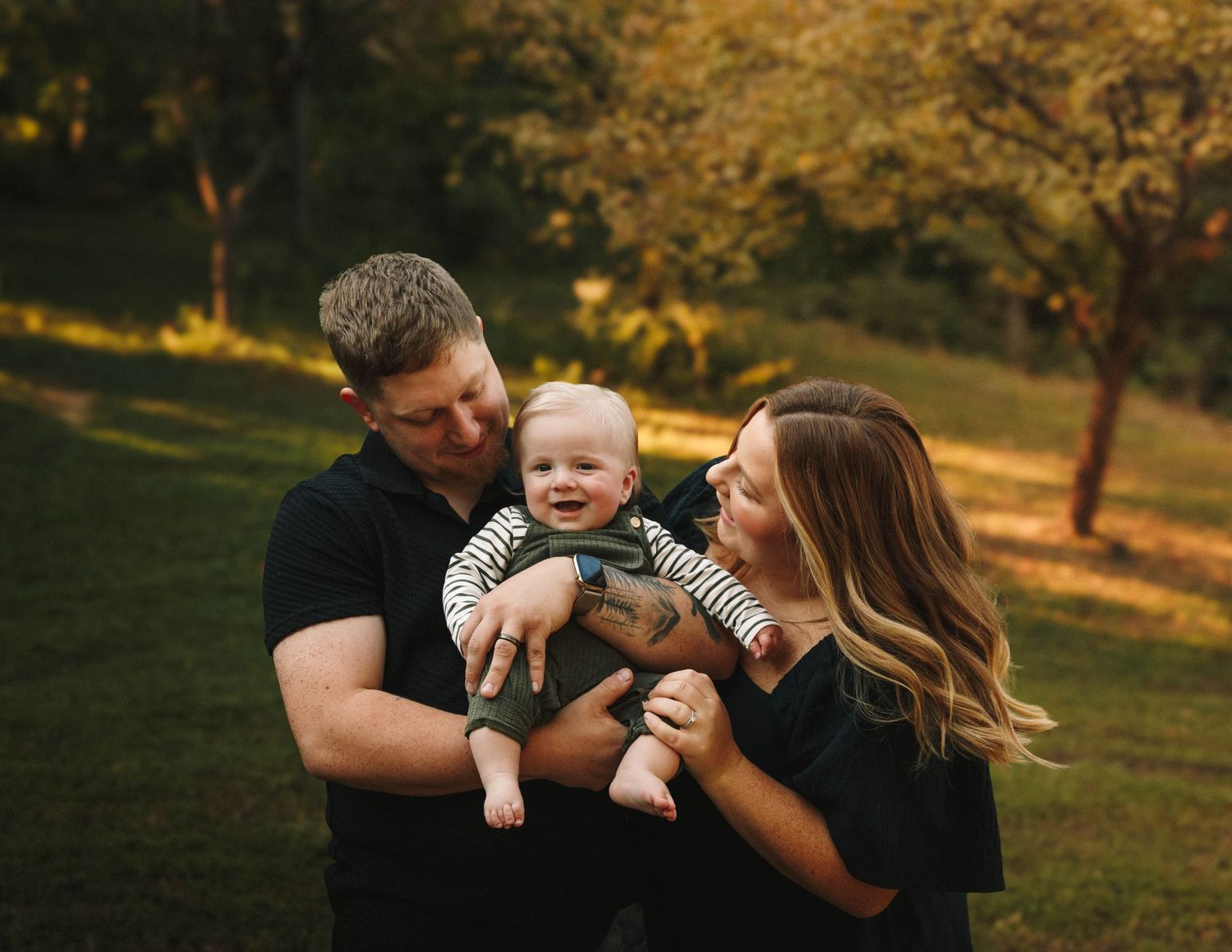 Family enjoying playful moments together in a sunlit autumn park during golden hour.