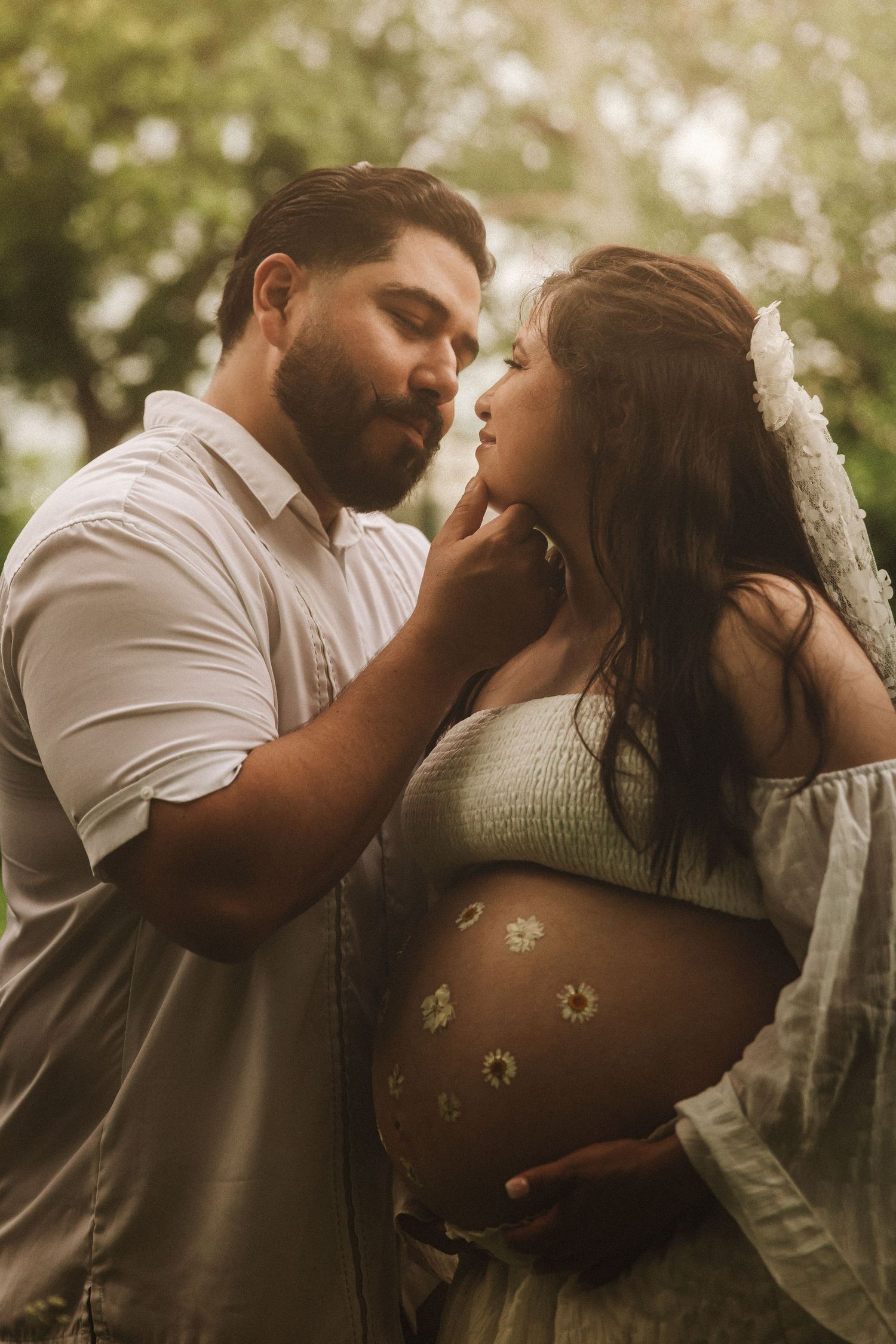 Romantic maternity photography outdoors showing painted belly art with small flowers in soft natural lighting.