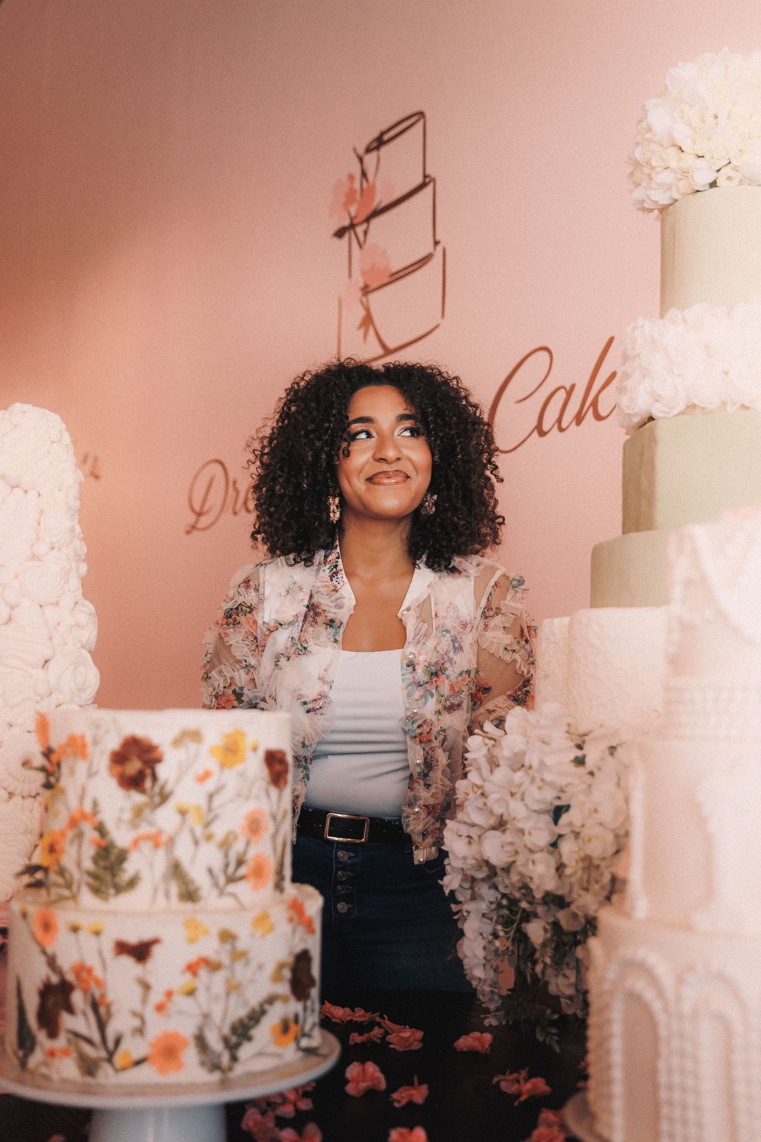 Stylish floral wedding cake display featuring pink bakery decor and delicate white frosting details.