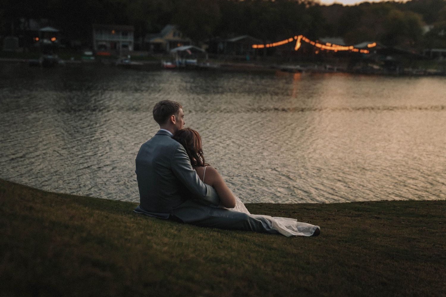 Silhouettes of people lounging by a serene lake at sunset, creating a peaceful and romantic atmosphere.
