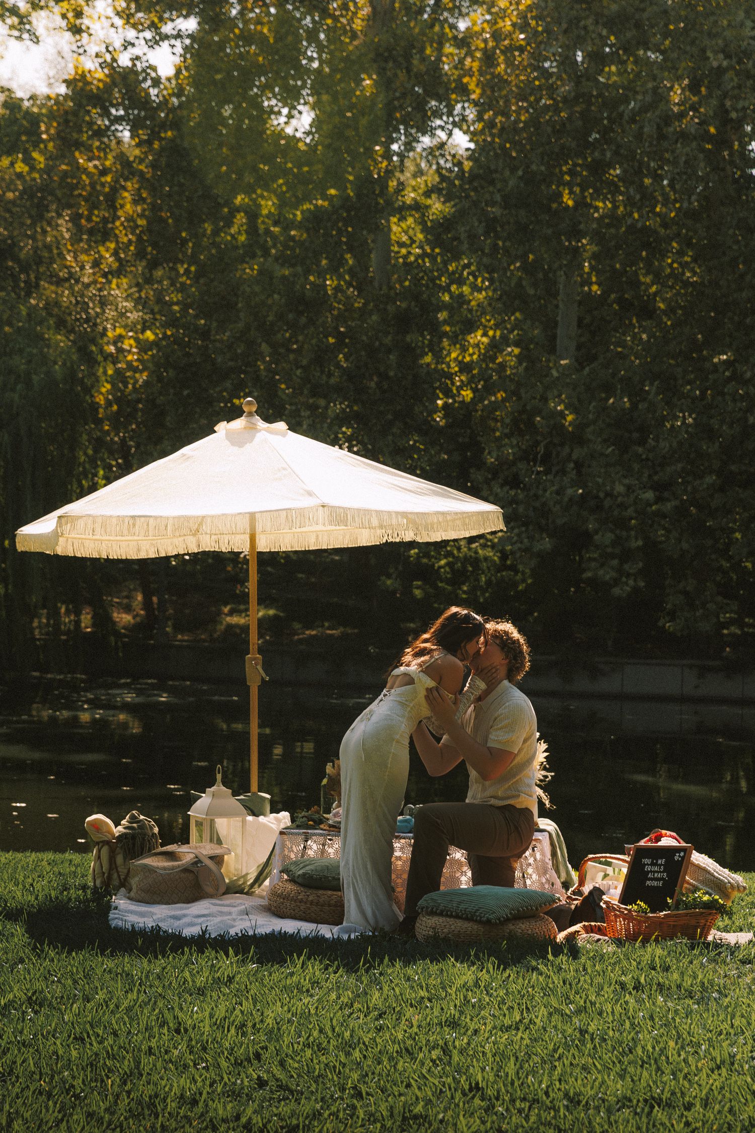 Group enjoying a picnic on green grass with decorative white parasols providing shade on a summer day.