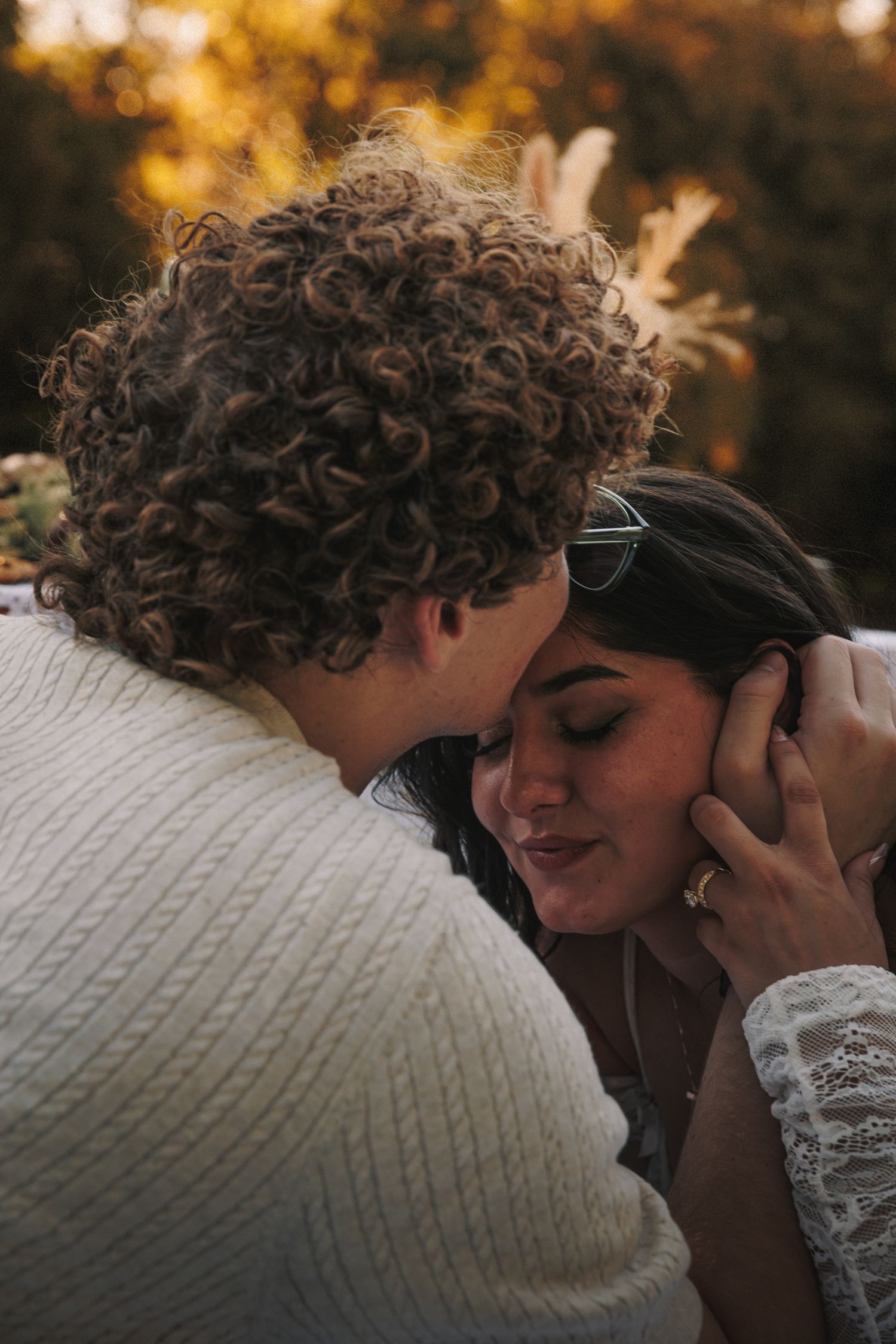 A tender intimate moment between a couple at sunset with golden bokeh in the background.