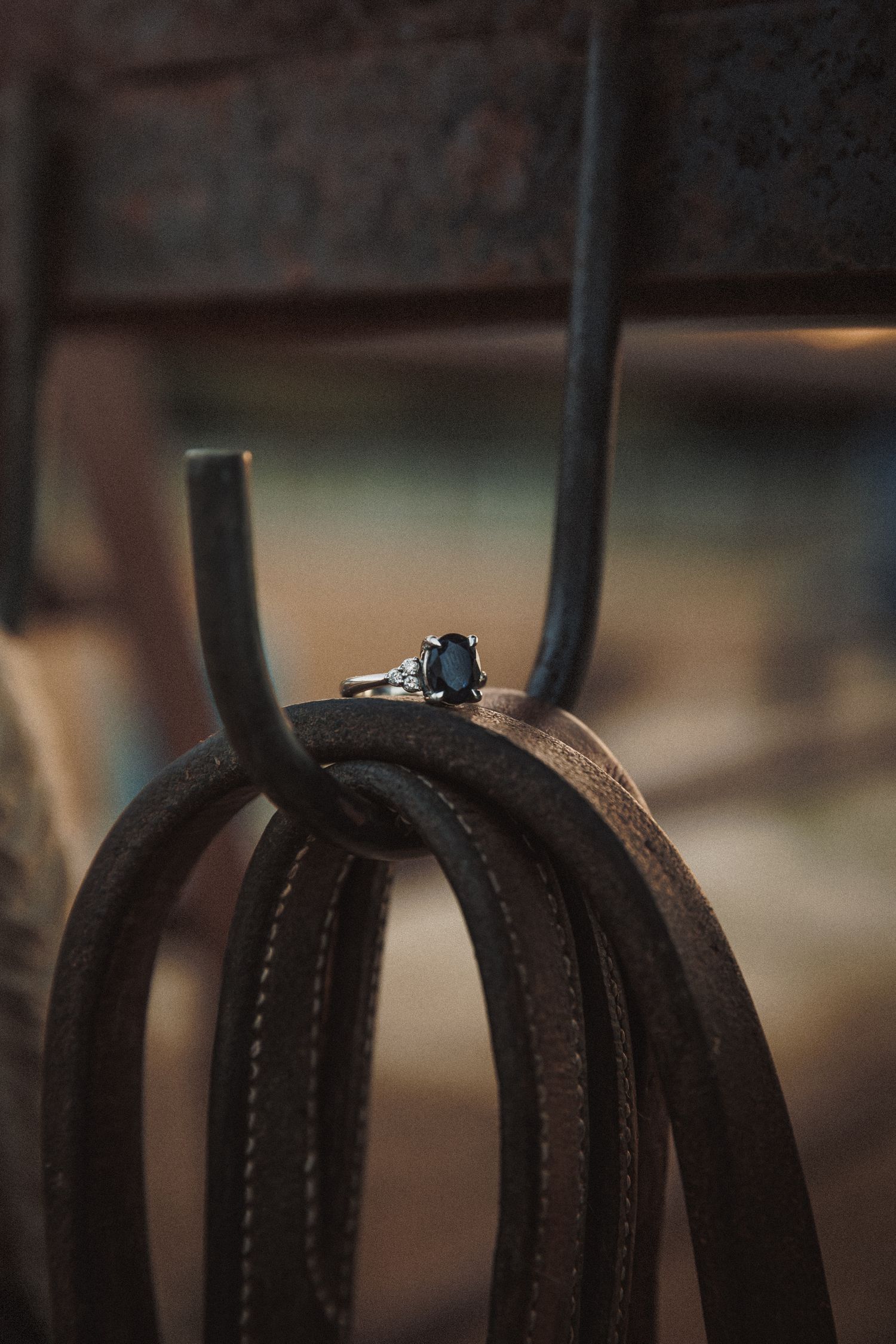 Elegant black oval gemstone engagement ring displayed on rustic leather straps.